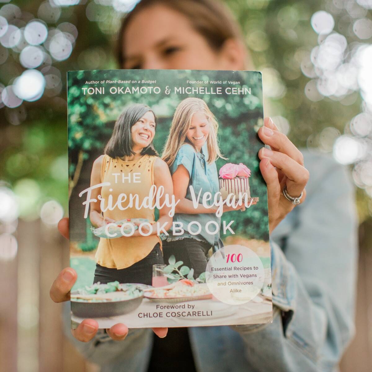 Author Michelle Cehn holding up the Friendly Vegan Cookbook. 