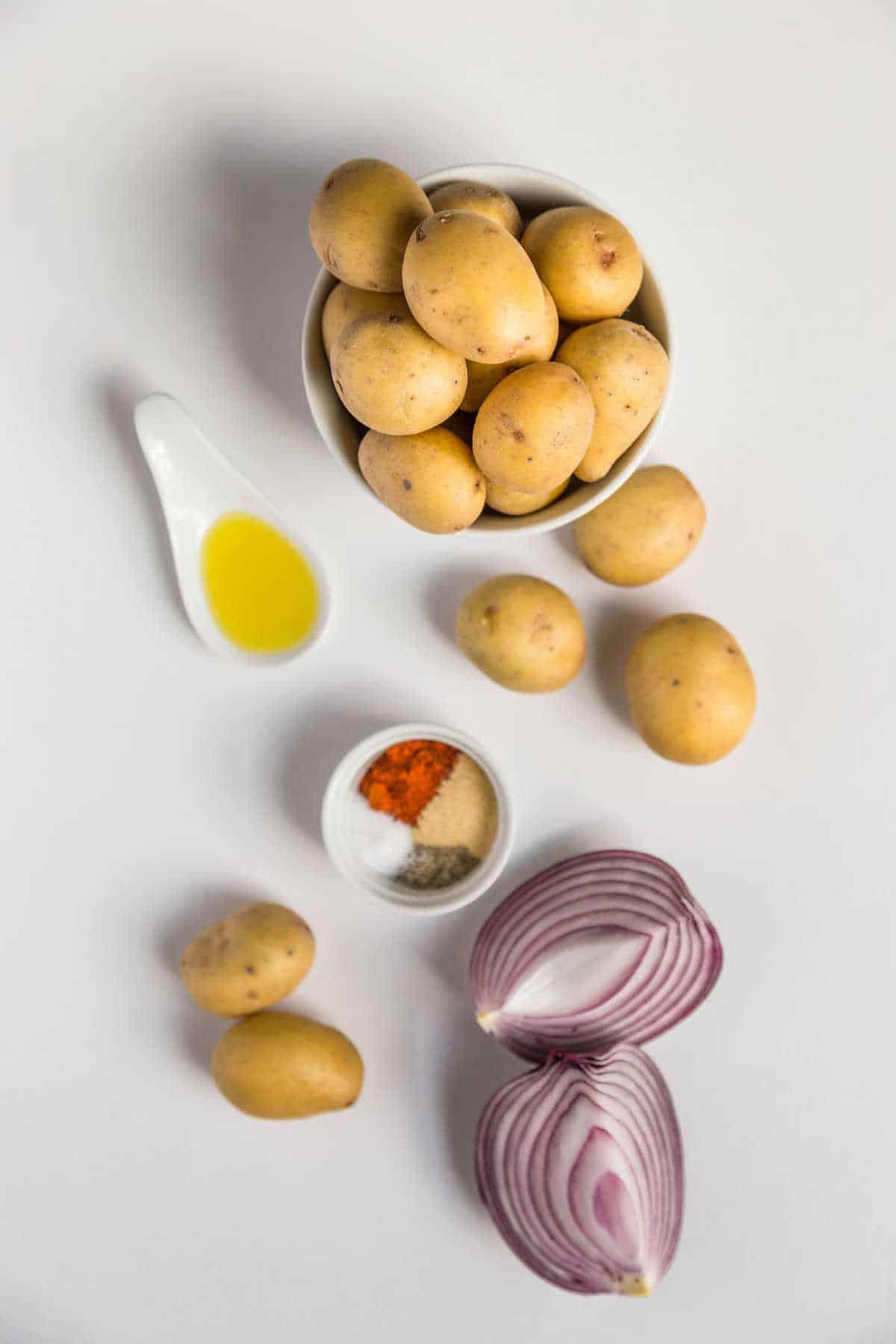 Ingredients for air fryer home fries measured and laid out on a light background.