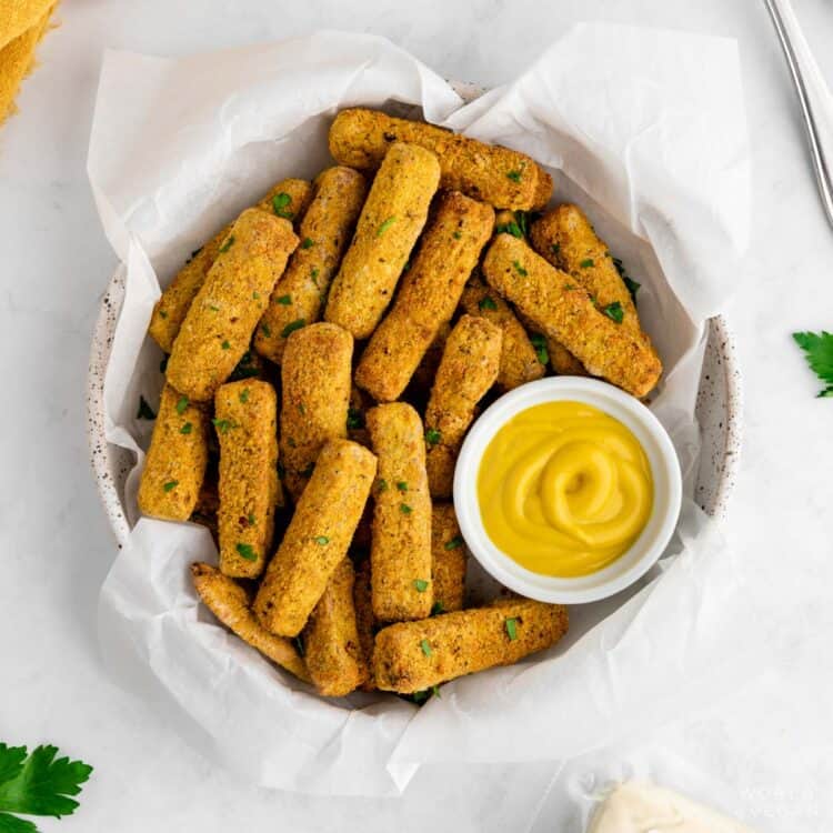 Rustic bowl of tofu fries made in the air fryer coated in nutritional yeast served with mustard.