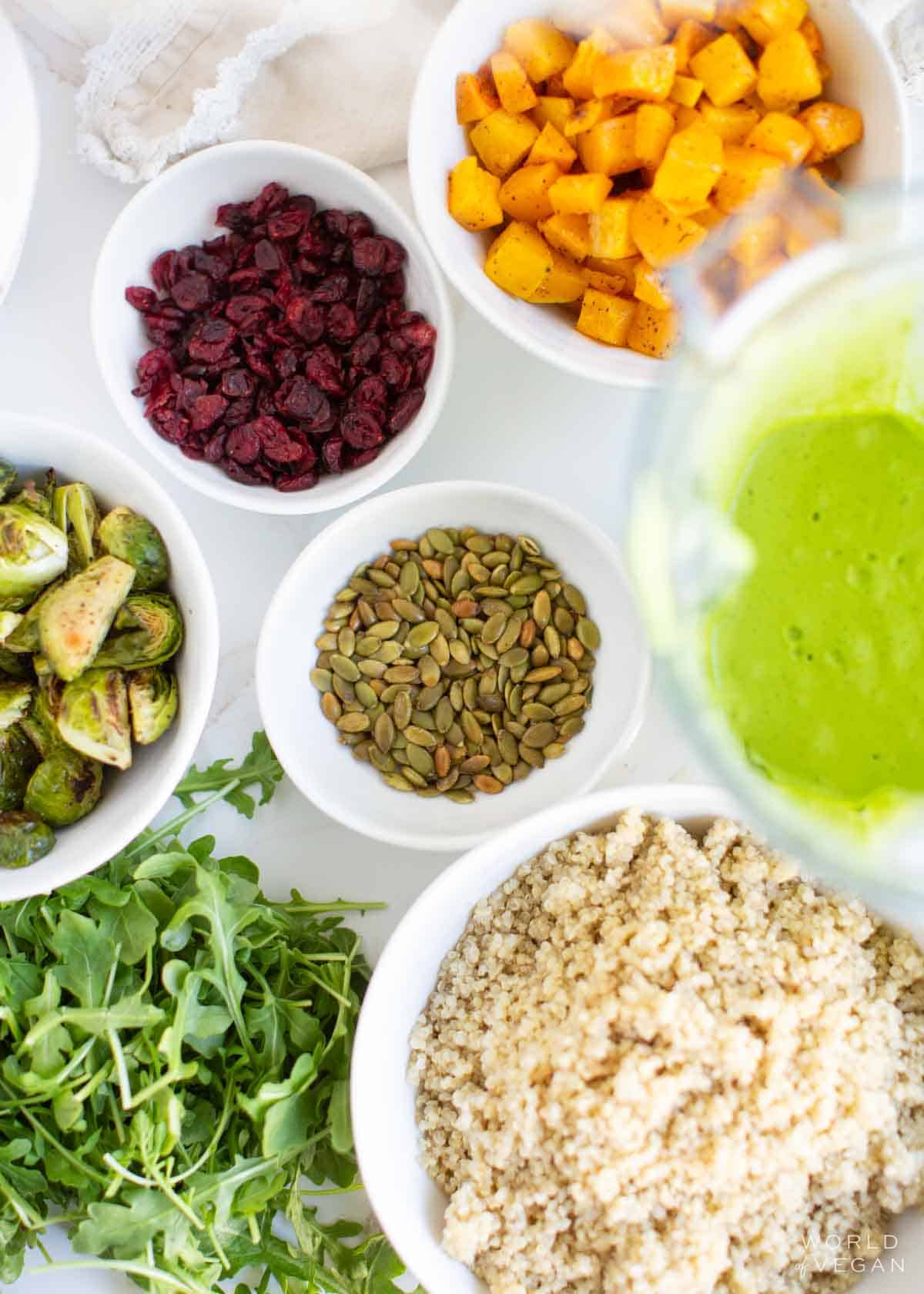 The ingredients for arugula quinoa salad in individual bowls scattered around.