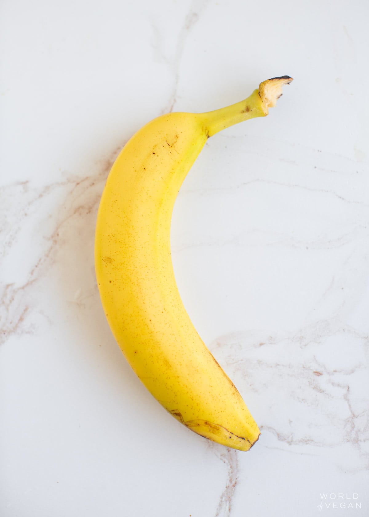 A yellow banana on a marble countertop.