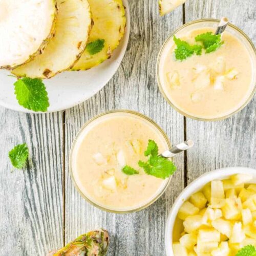 best pineapple banana smoothie served in glassed topped with fresh pineapple and mint leaves