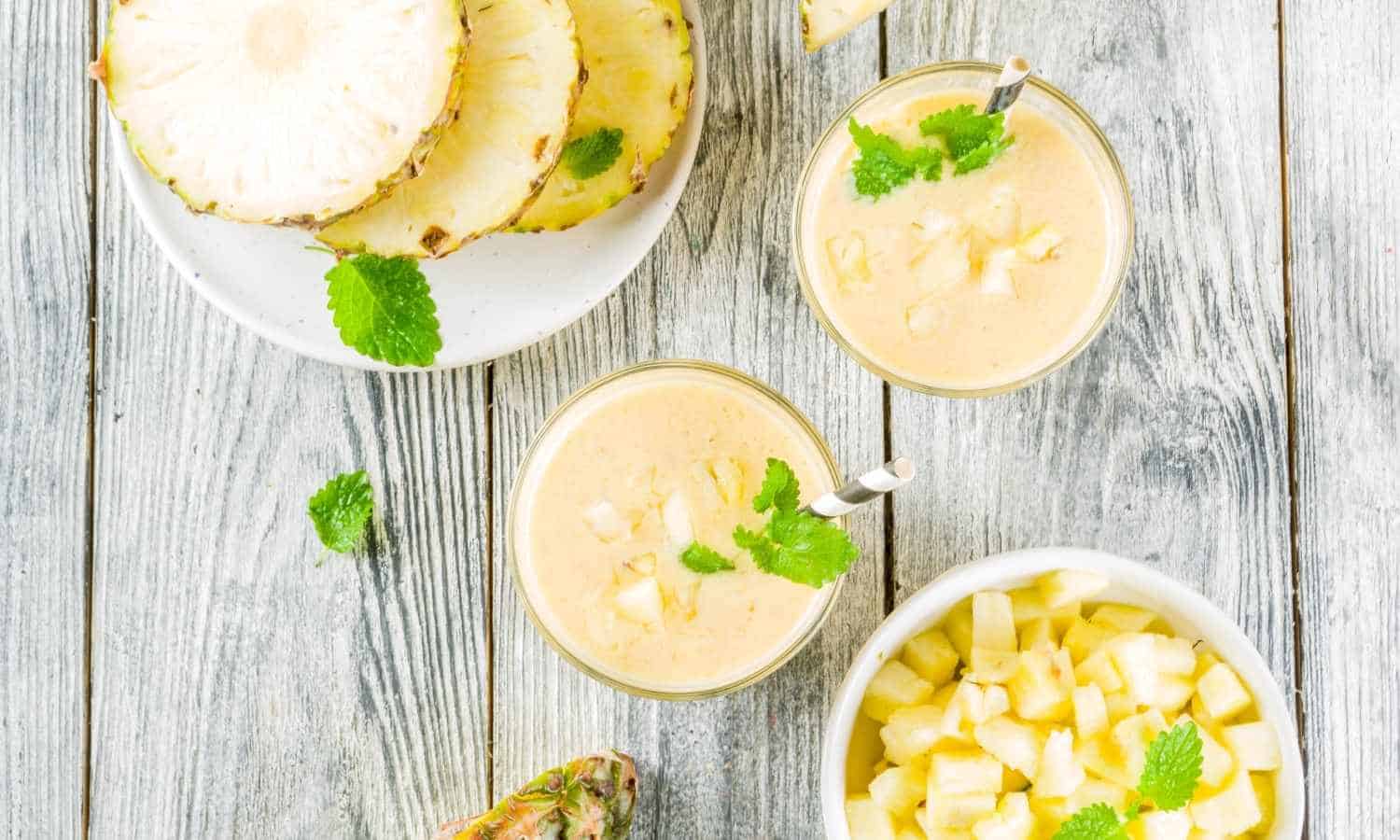 best pineapple banana smoothie served in glassed topped with fresh pineapple and mint leaves