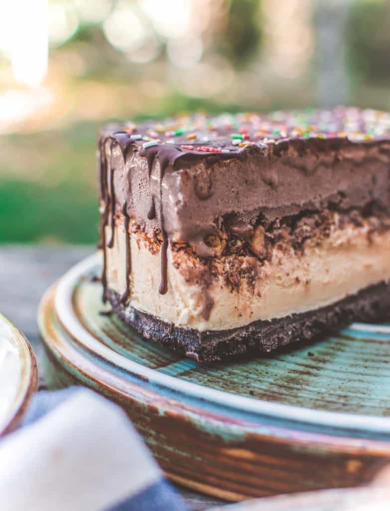 double level vegan ice cream cake with chocolate drizzle top and oreo crust and rainbow sprinkles