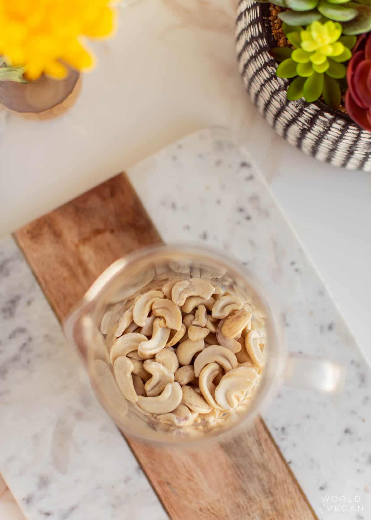 Raw cashews in a glass measuring cup.