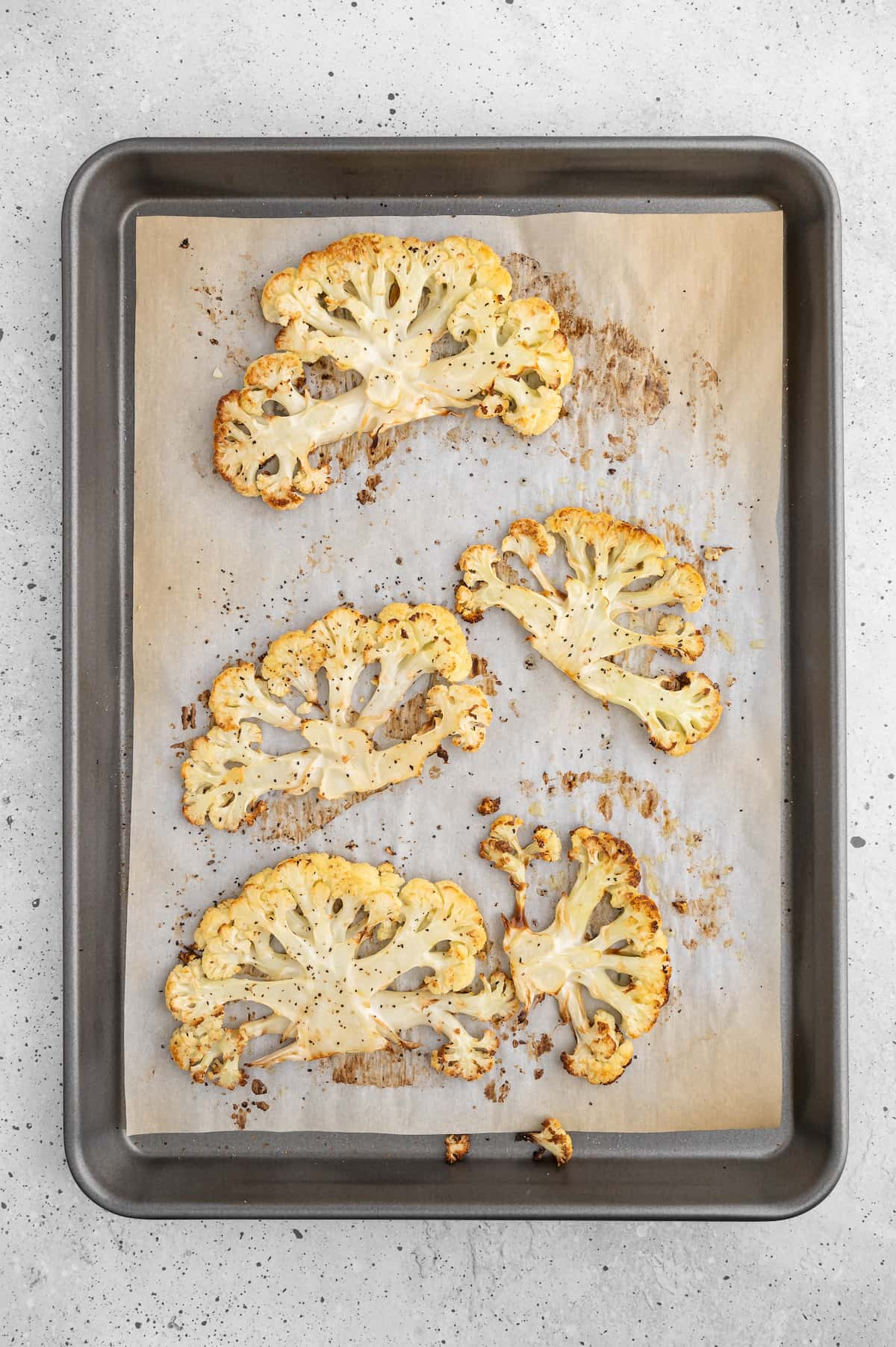 Roasted cauliflower steaks on a baking tray.