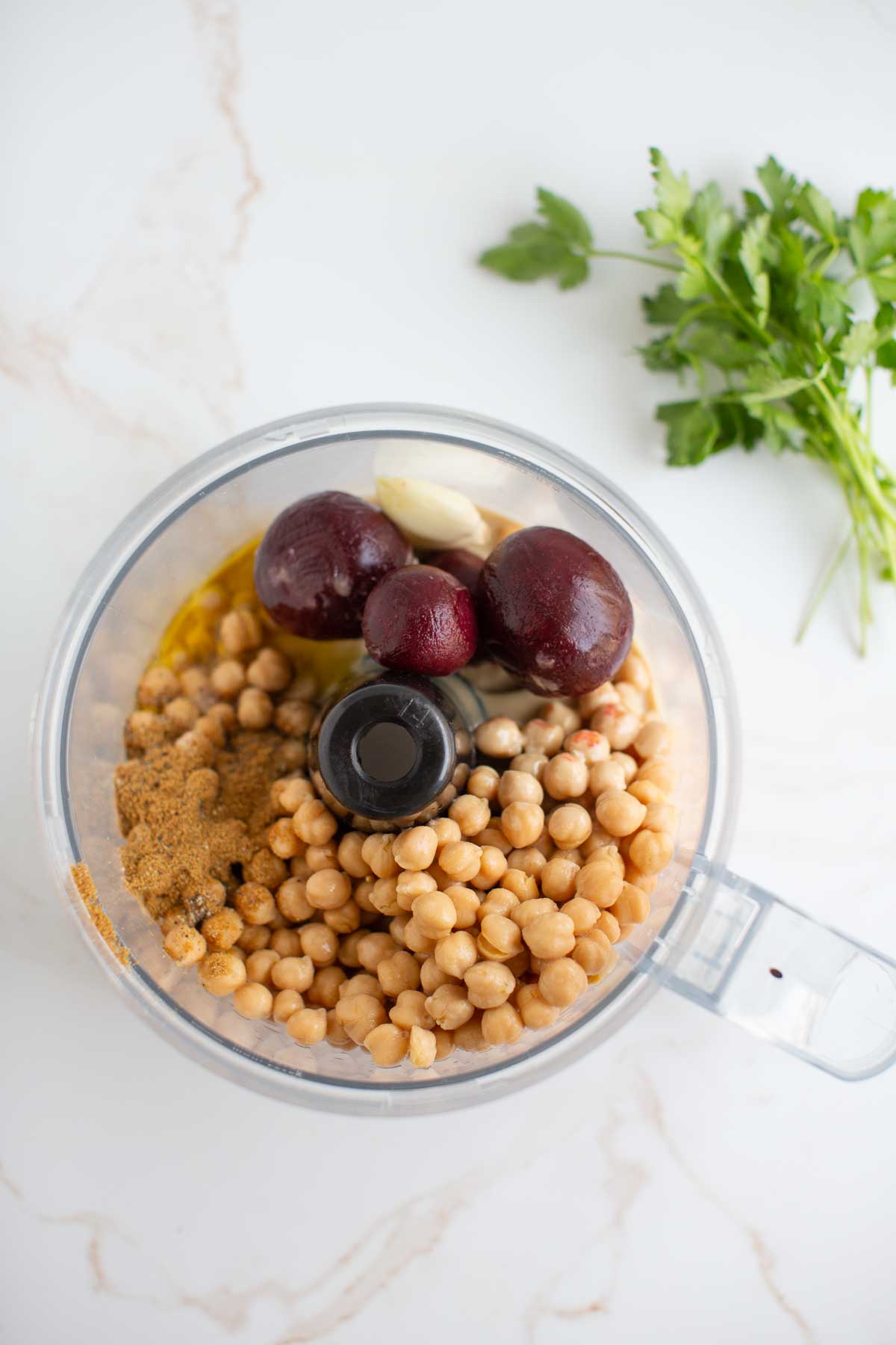 Ingredients for pink beet hummus in a food processor on a kitchen counter. 