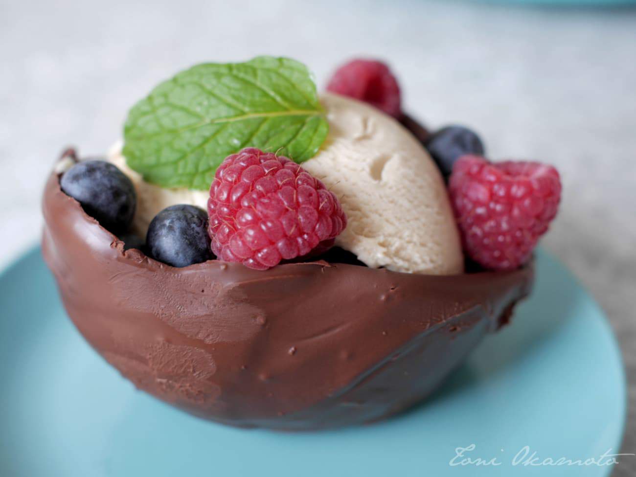 vegan chocolate bowl filled with vanilla ice cream and garnished with blueberries, raspberries, and a mint leaf