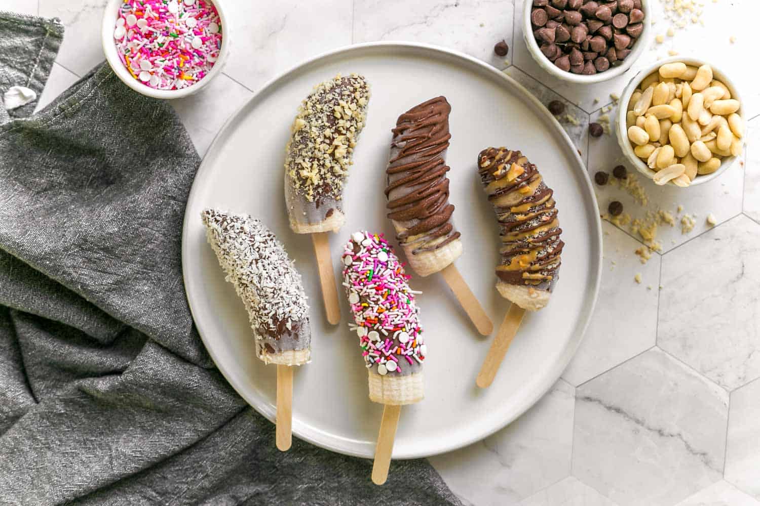 Chocolate Covered Frozen Banana Pops With Various Toppings