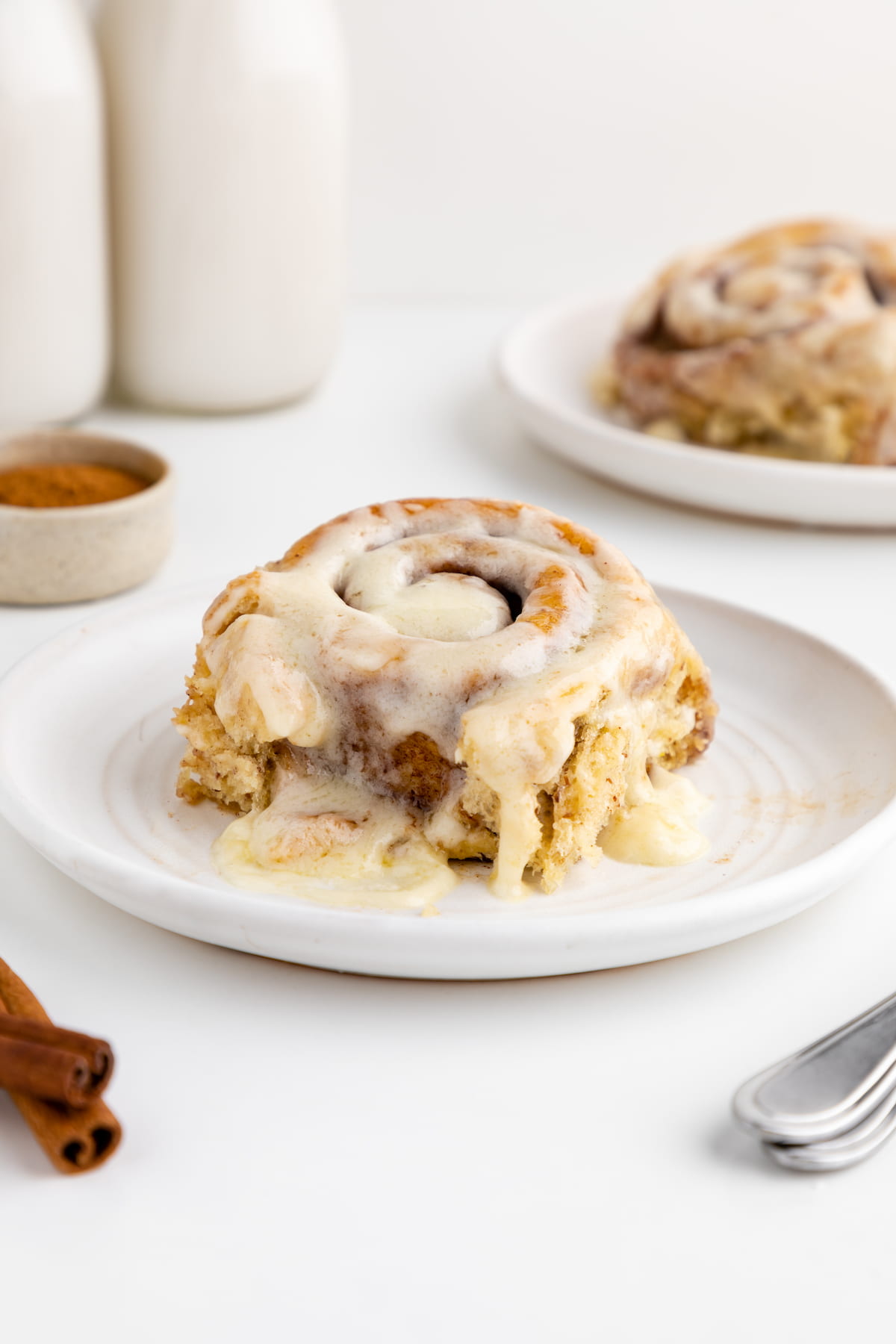 Vegan cinnamon roll on a plate, drizzle with frosting.