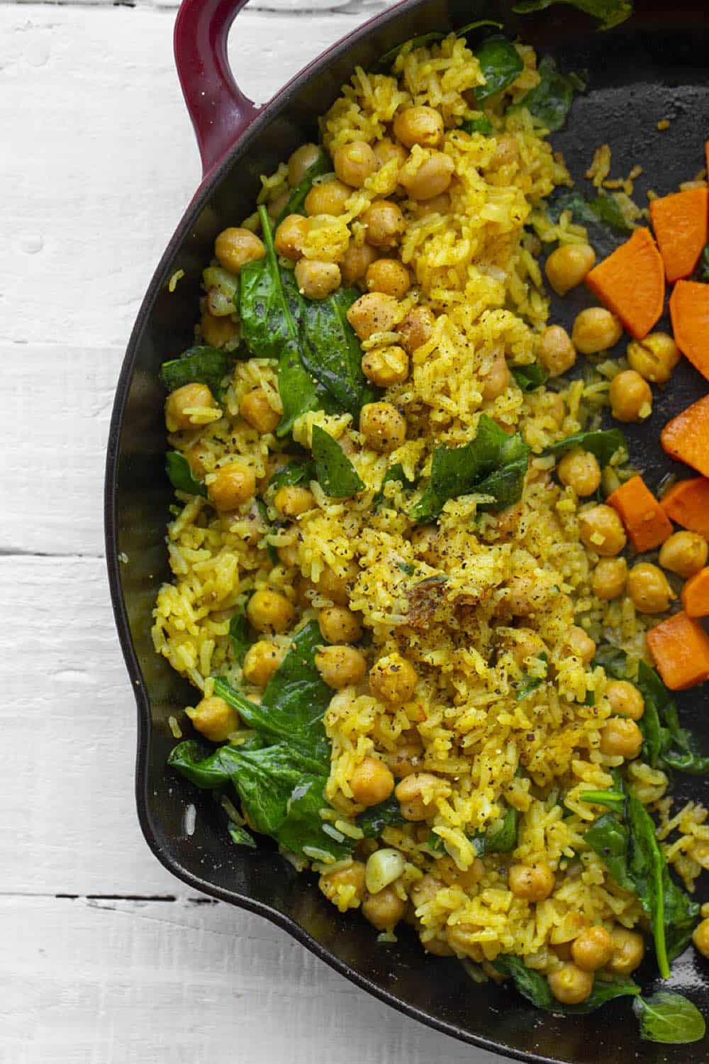 coconut curry rice and chickpeas in a cast iron pan with green garnish