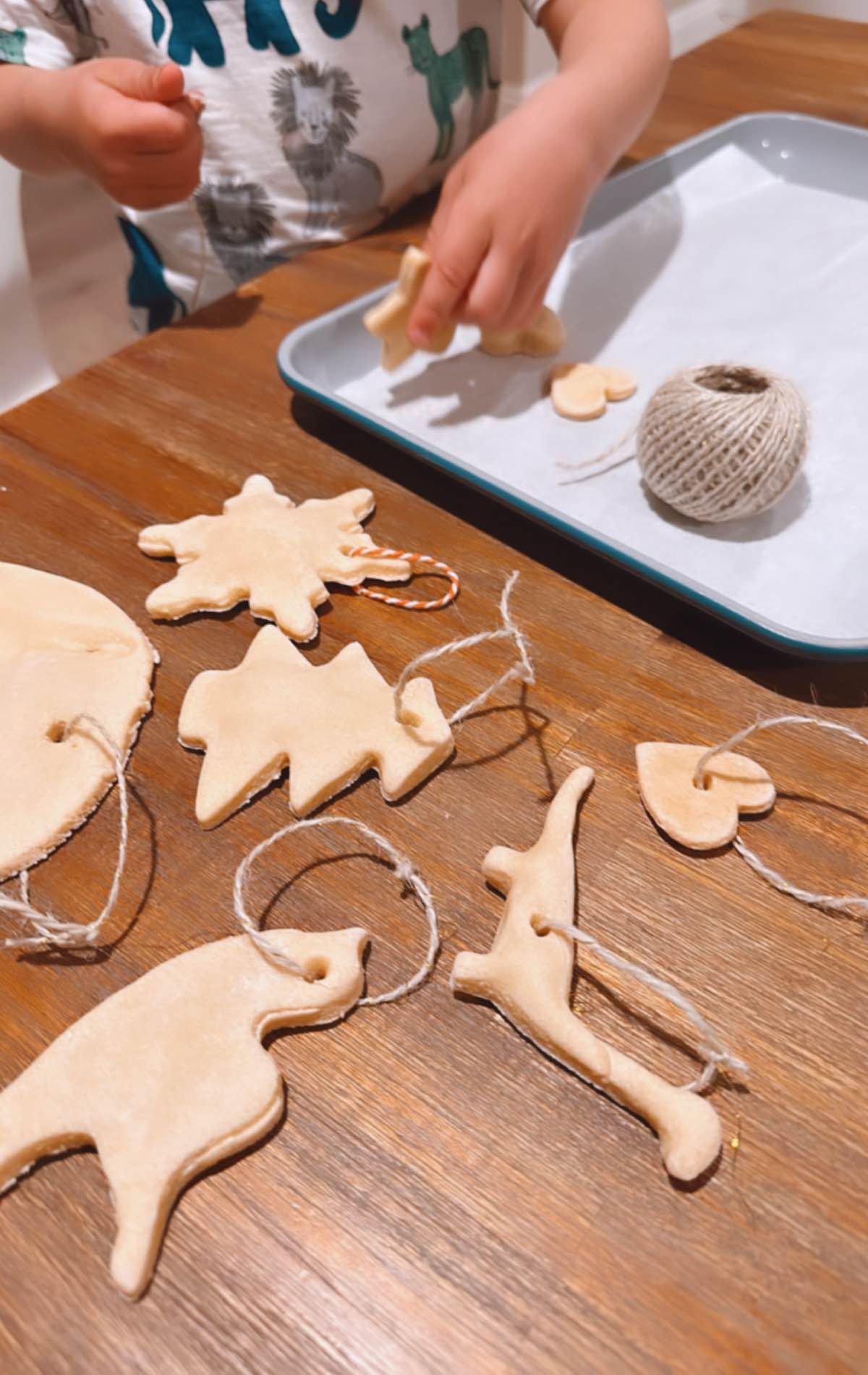 Kid threading kitchen twine through DIY salt dough ornaments. 