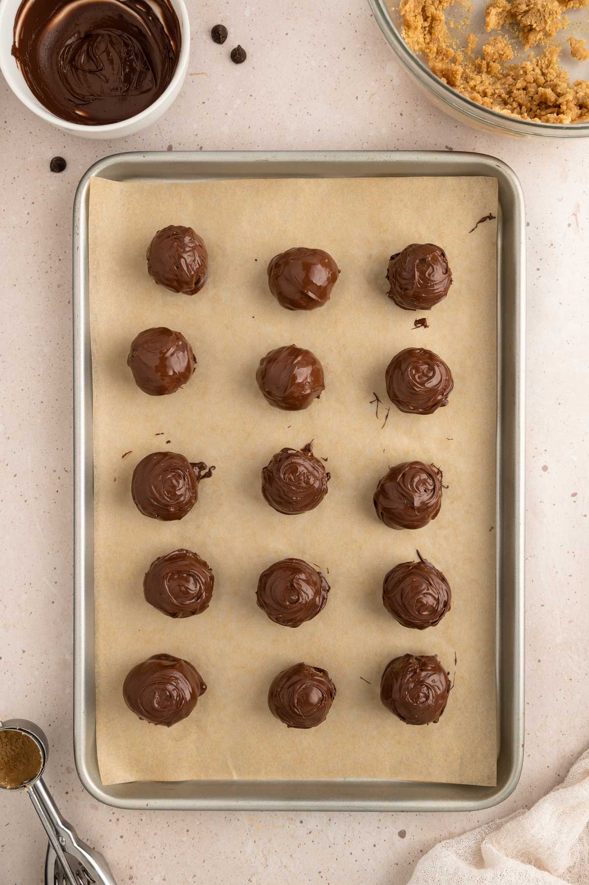 Chocolate-coated cookie dough balls on a baking sheet.