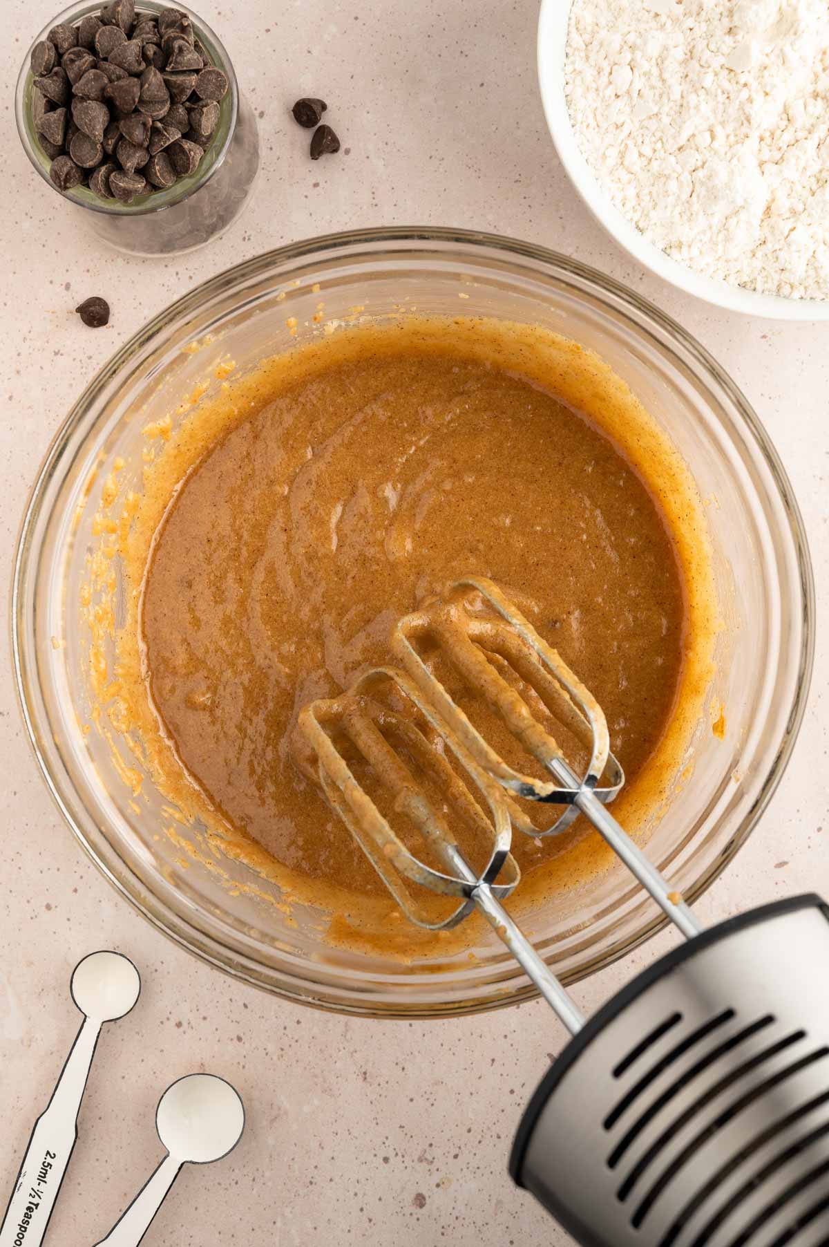 Cookie dough batter being mixed in a glass bowl.