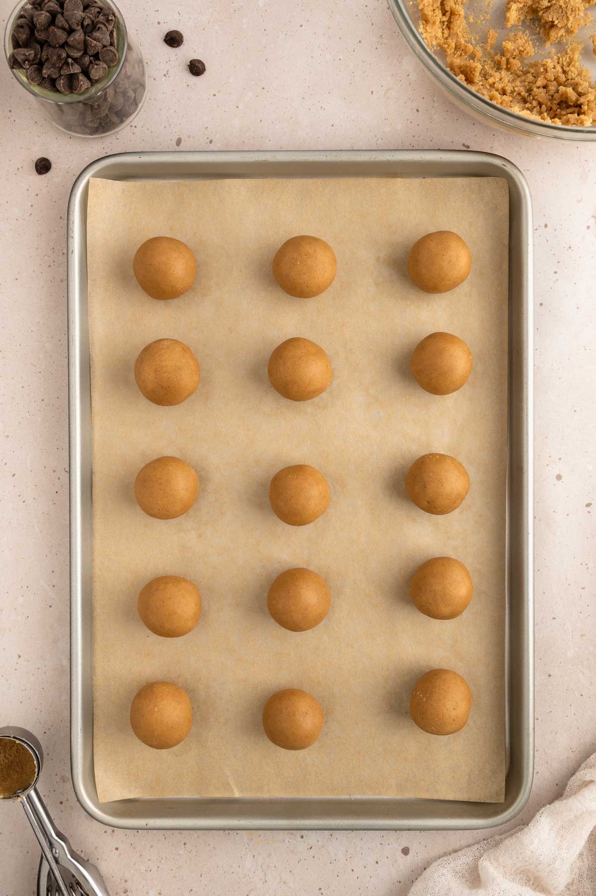 Cookie dough balls arranged on a baking sheet.