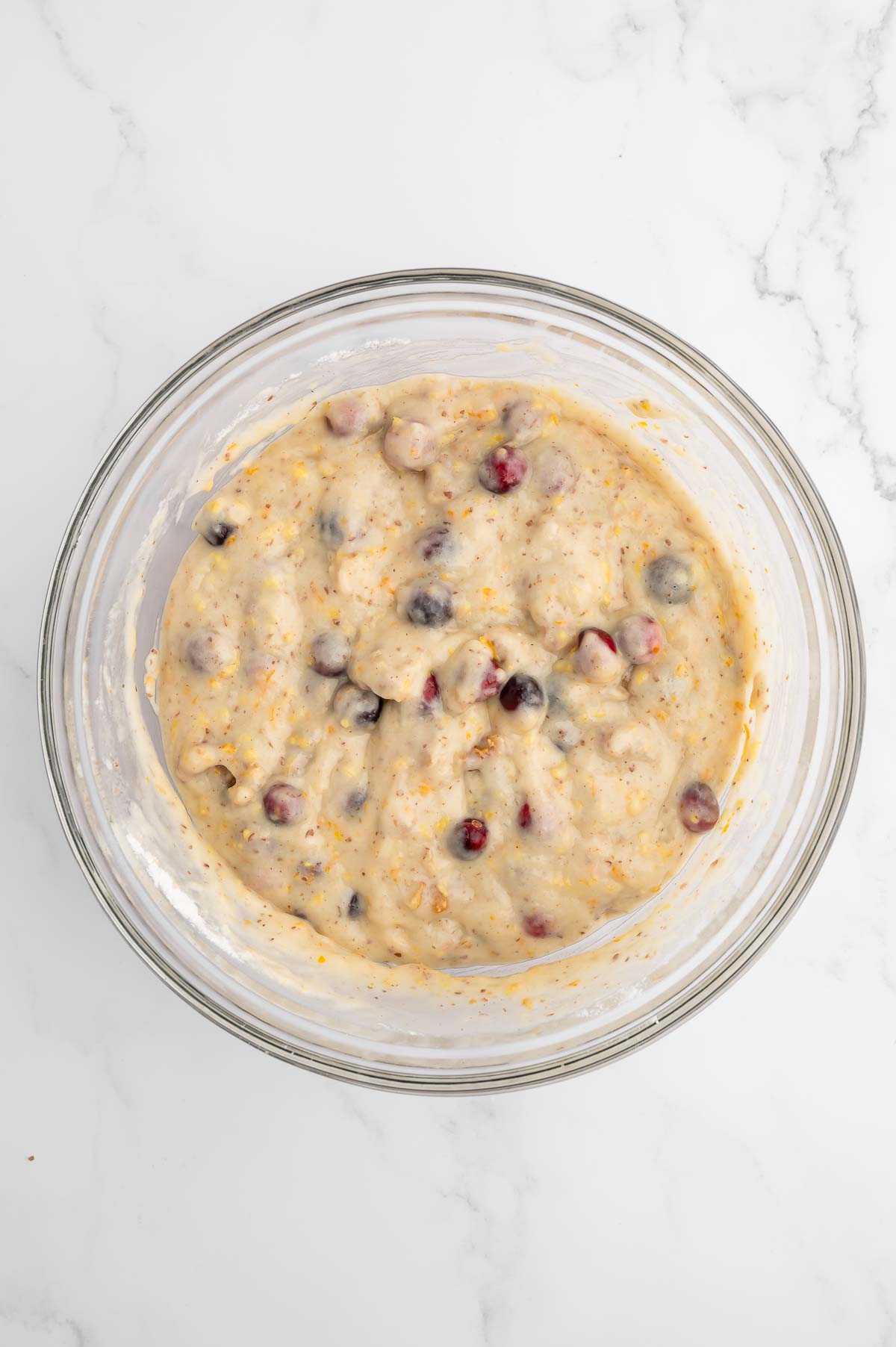 A bowl of batter with berries mixed in.