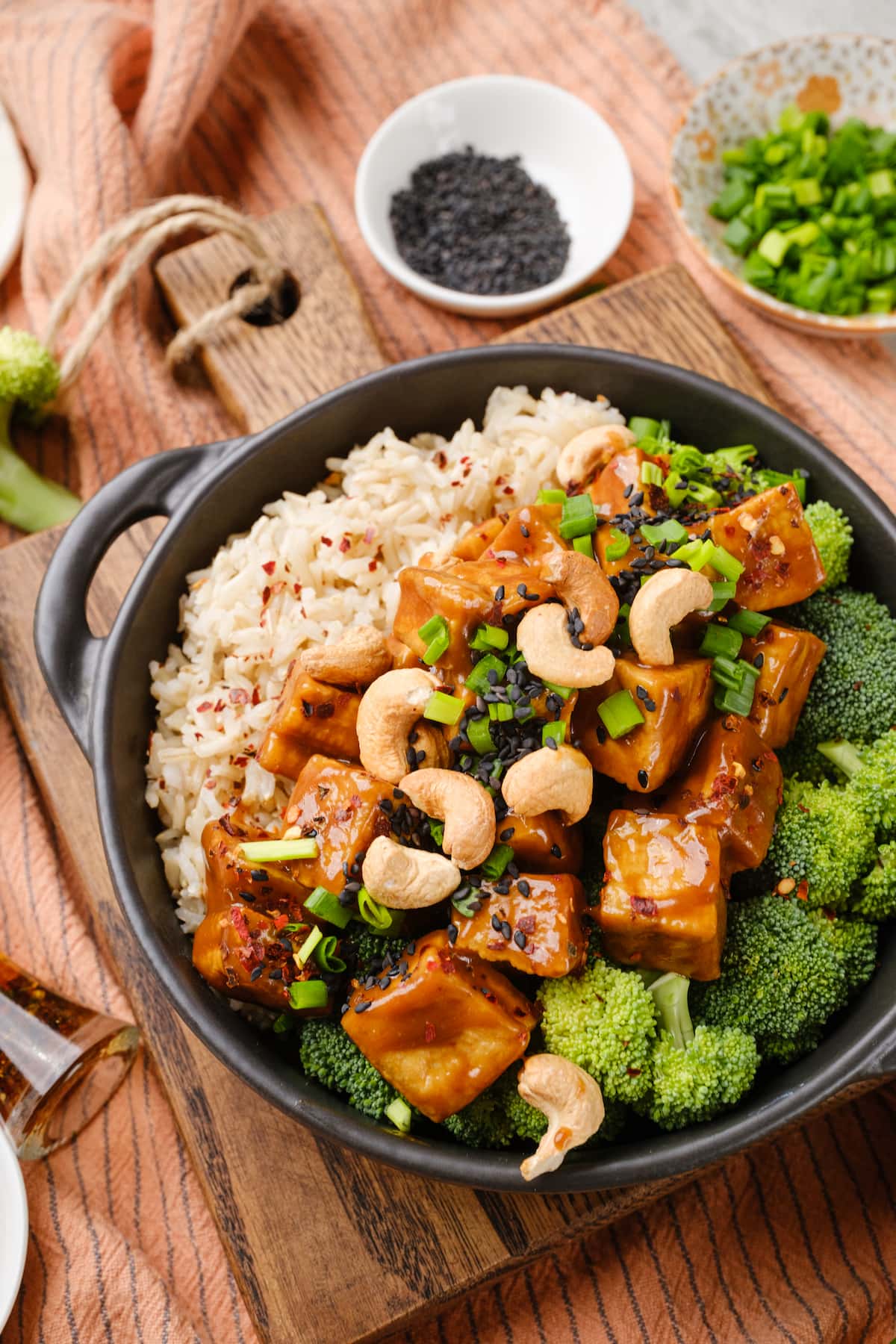 A bowl of crispy tofu Szechuan-style with rice, broccoli, and cashews.