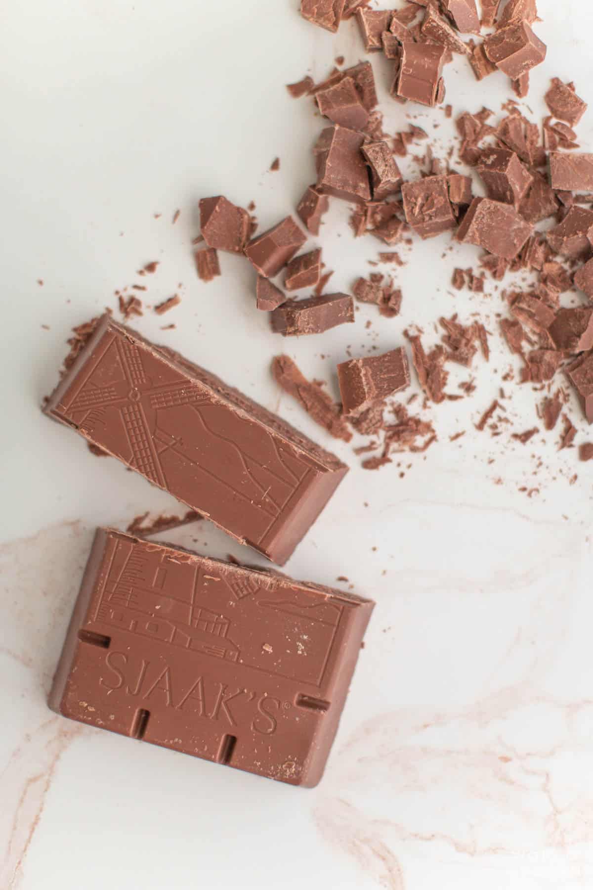 Block of vegan milk chocolate from Sjaaks broken into pieces on the countertop.  