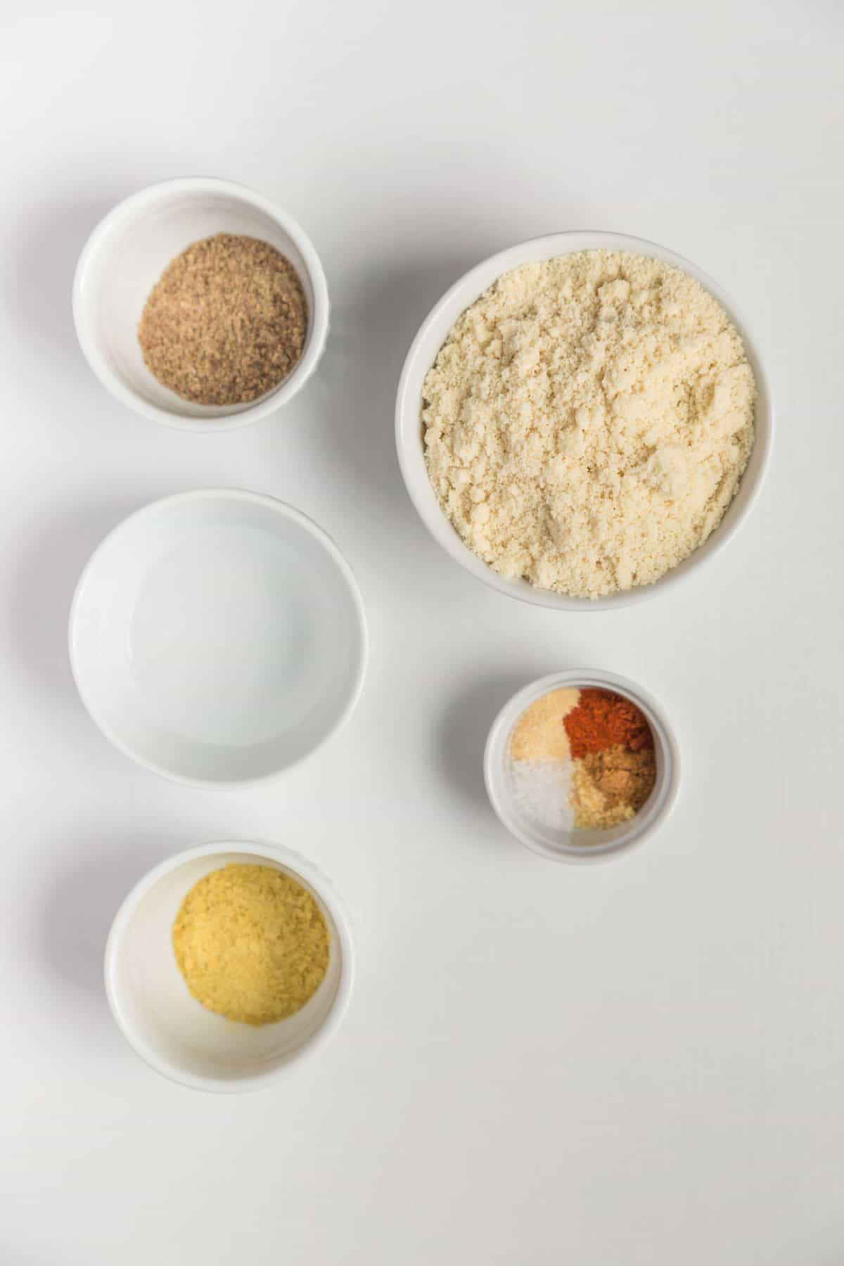 A top-down shot of ingredients for almond flour crackers against a white background.