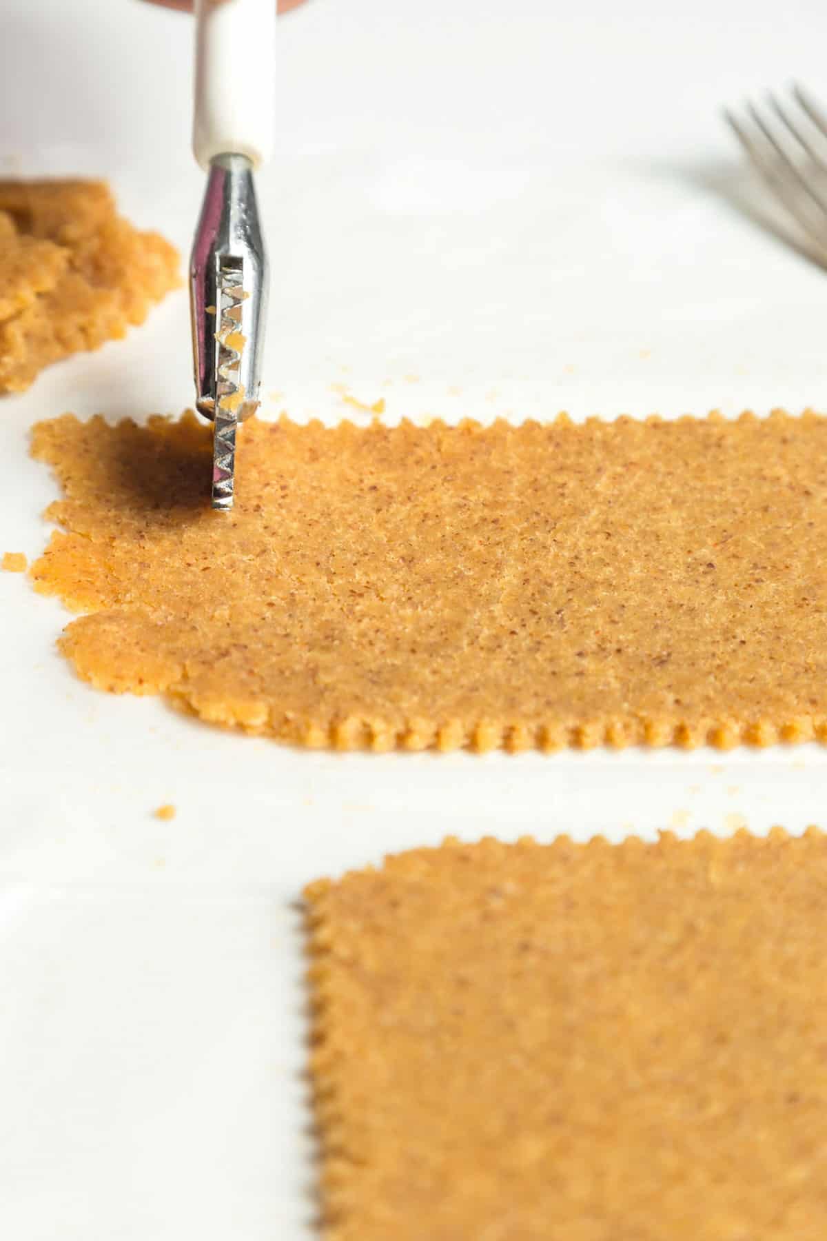 Almond flour dough flattened and scored on a white background.