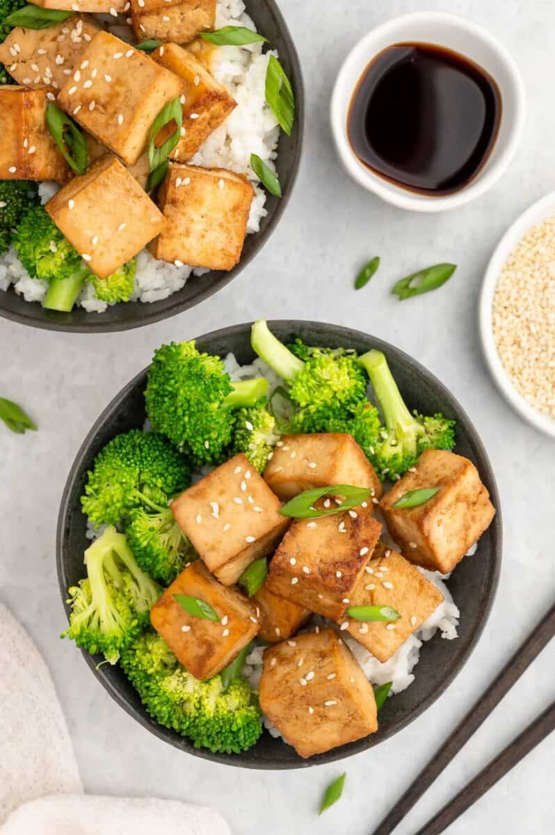 Two bowls of marinated tofu served over rice and broccoli.