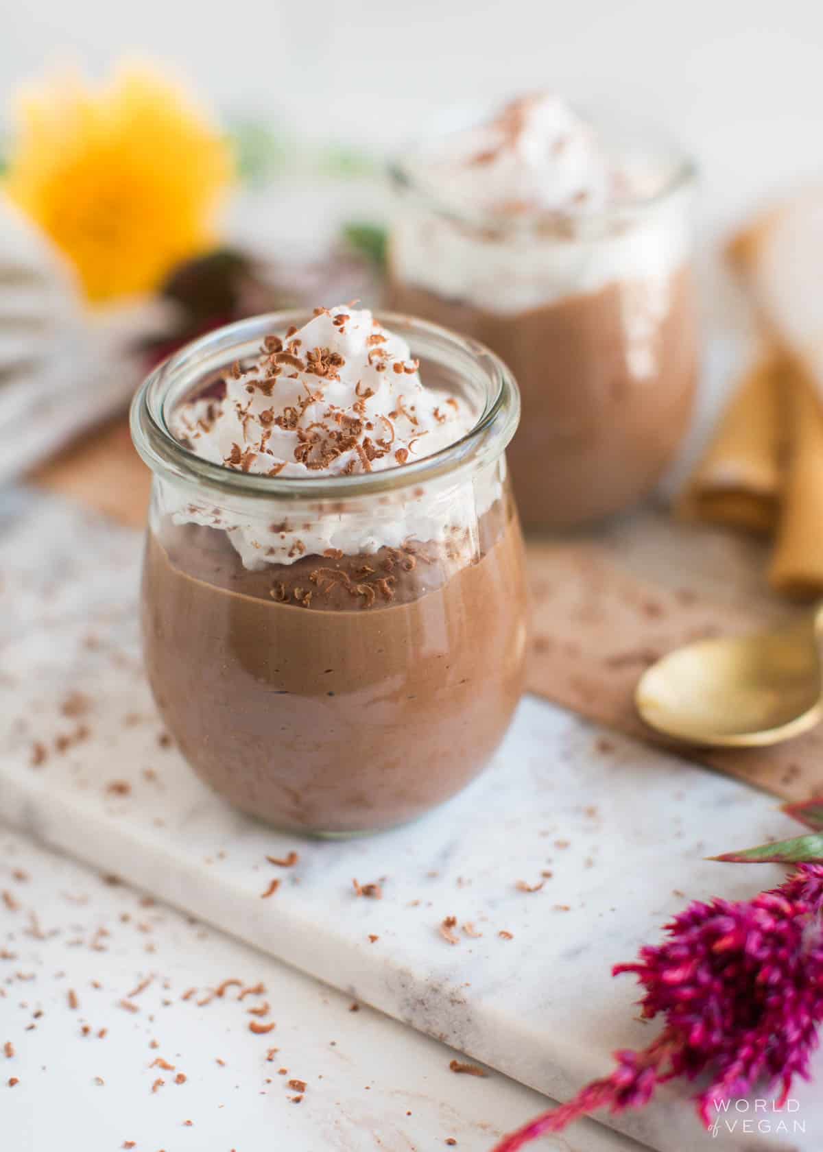 Vegan chocolate pudding in jars, topped with vegan whipped cream and chocolate shavings.