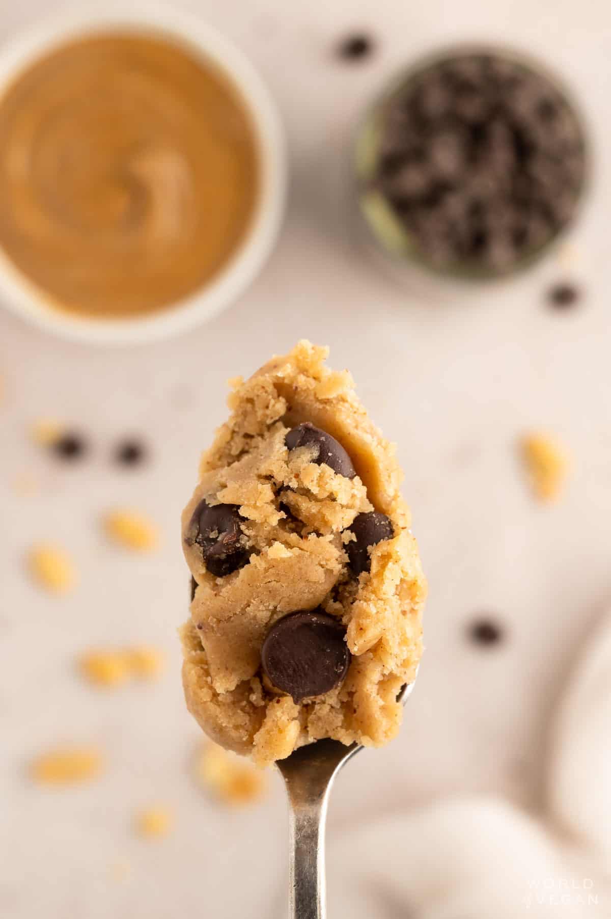A silver spoon of edible peanut butter cookie dough with chocolate chips.