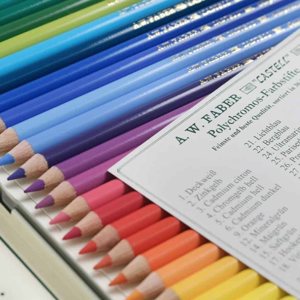 A large tin of colorful colored pencils laid out set with a card describing the colors.