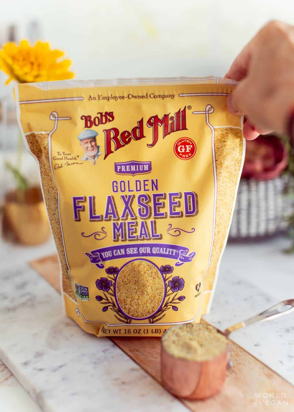 A hand reaching for a package of golden flaxseed meal.