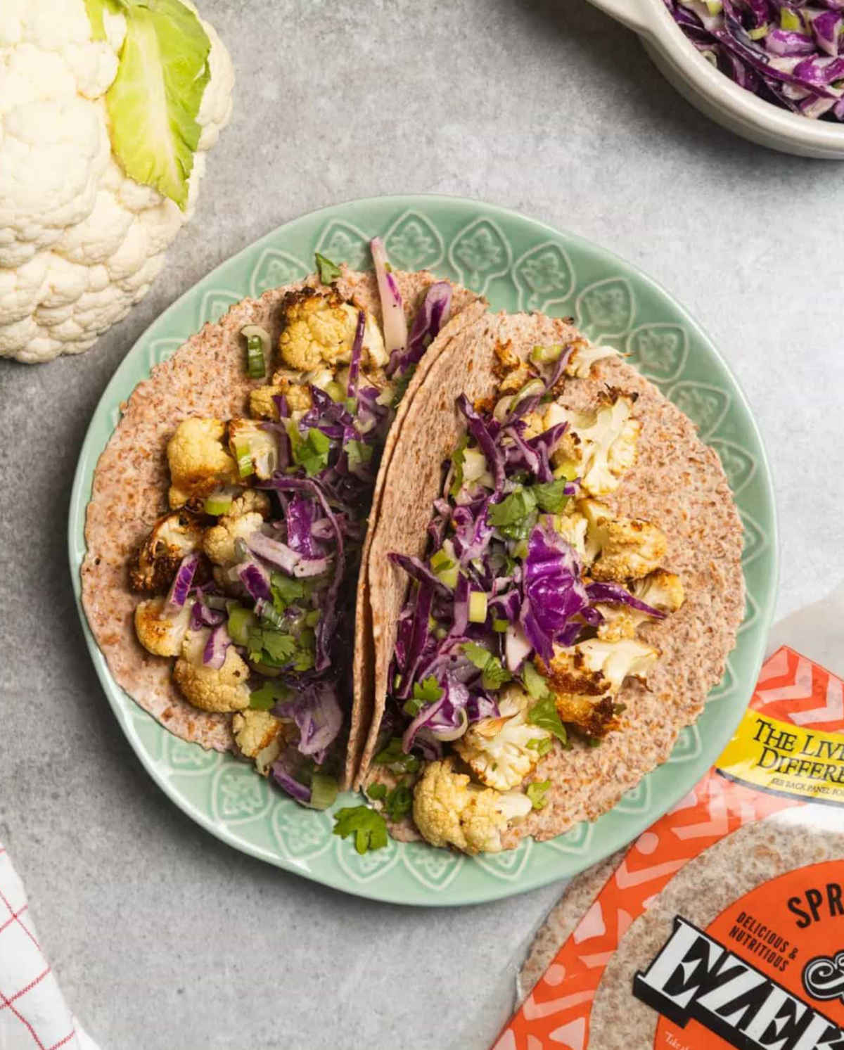 A package of Food for Life sprouted tortillas next to plate of cauliflower tacos.