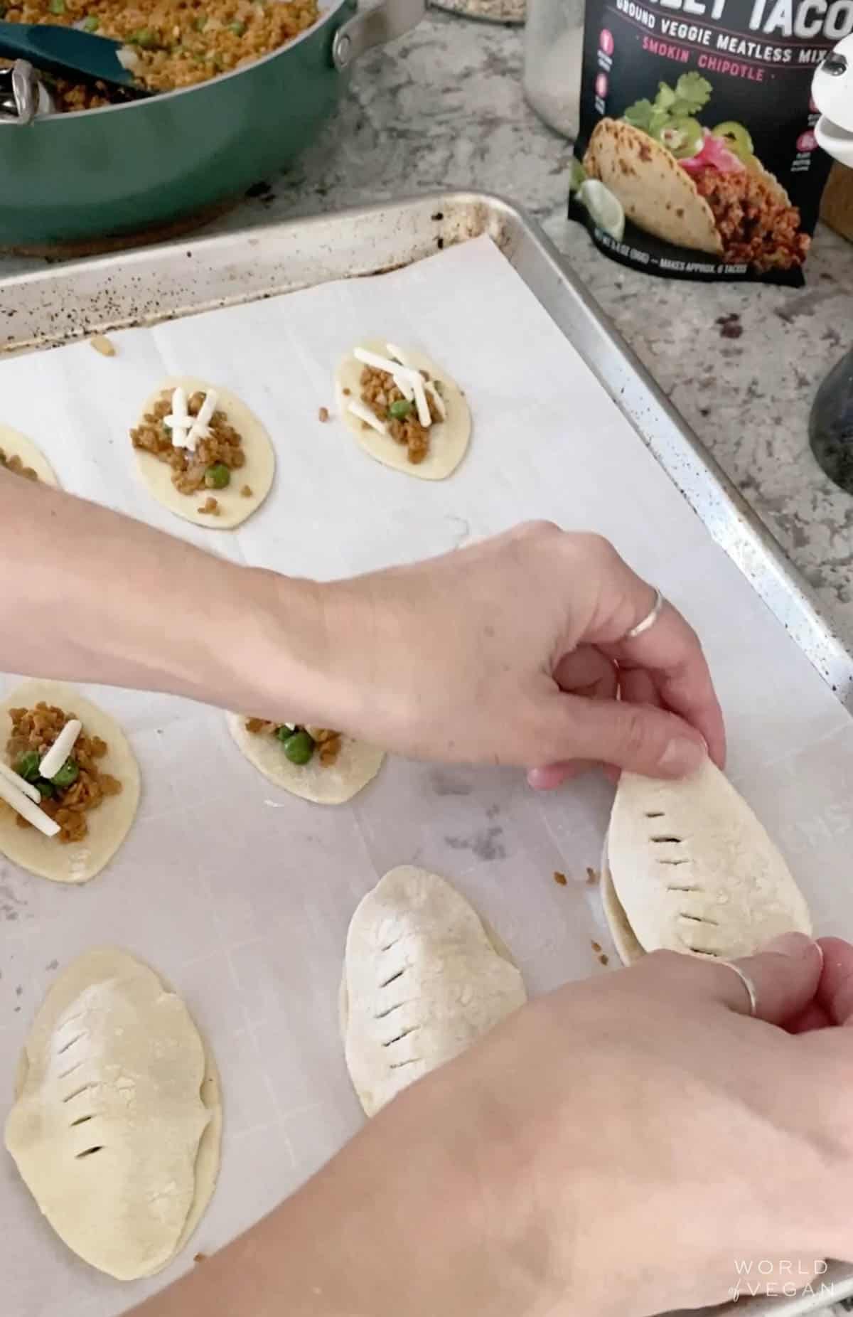 Placing the top layer of pastry dough over the filling to create a football shape for superbowl.