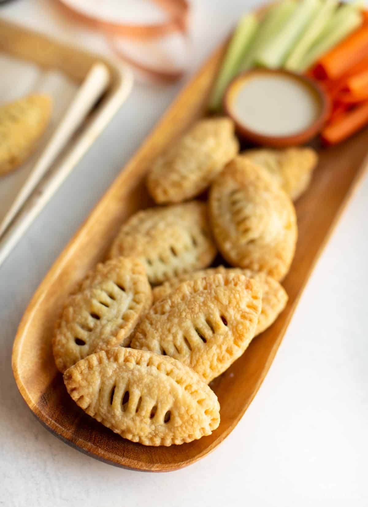 Football shaped vegan puff pastry appetizers on a serving board.