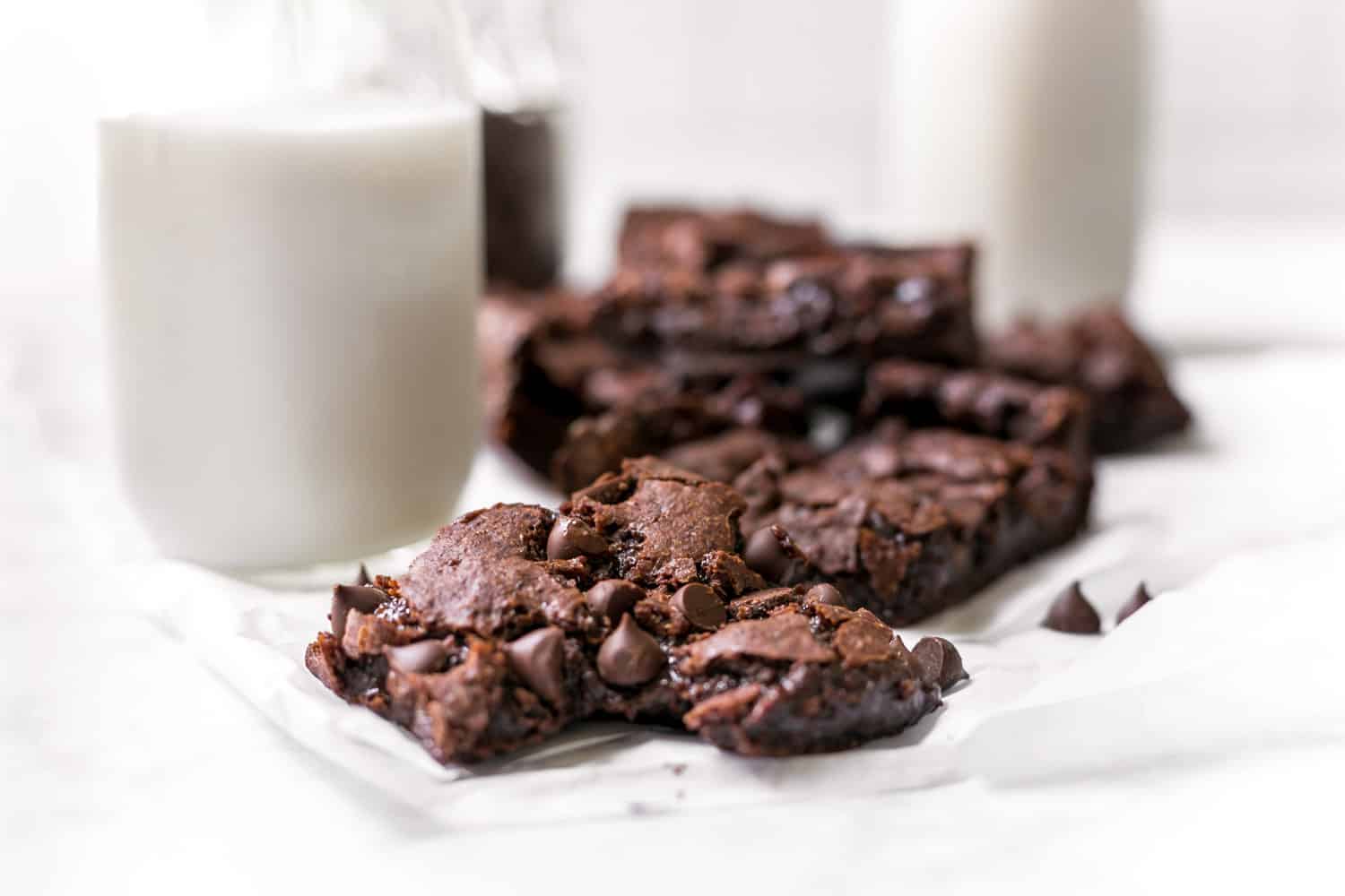 plate of vegan brownies with a glass of non-dairy milk in the background