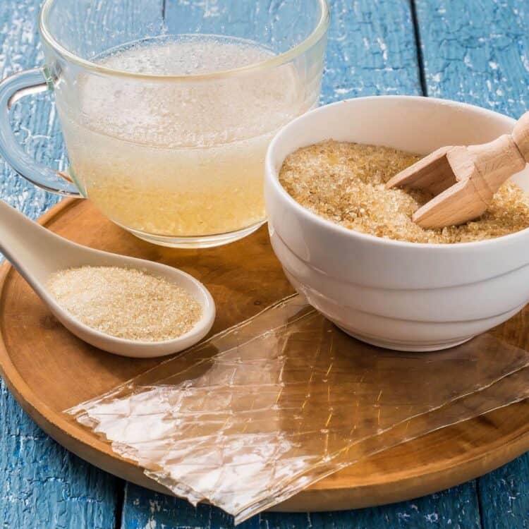 Gelatin on a wooden tray in different forms—powder, strips, granules, and liquid.