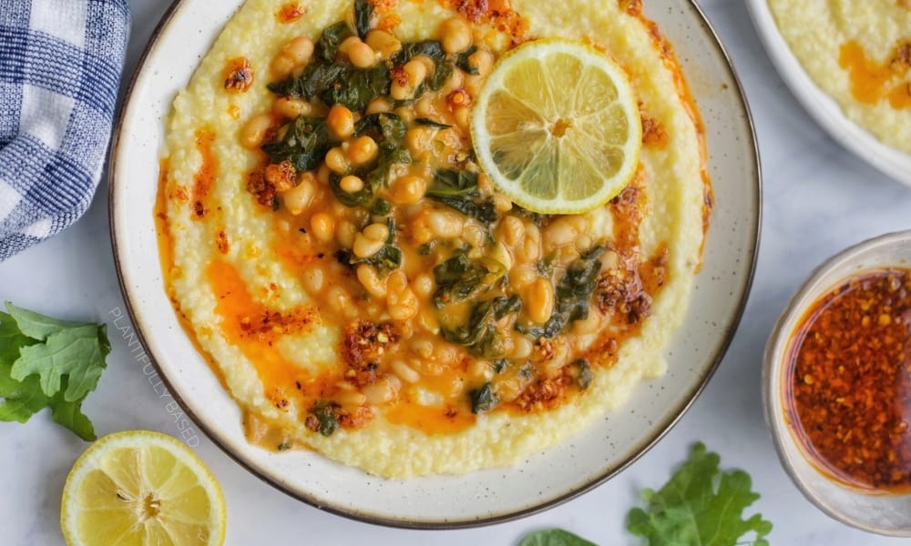 Vegan Polenta With Greens and Beans Recipe With Beans from Plantifully Based in a bowl with ingredients around it.