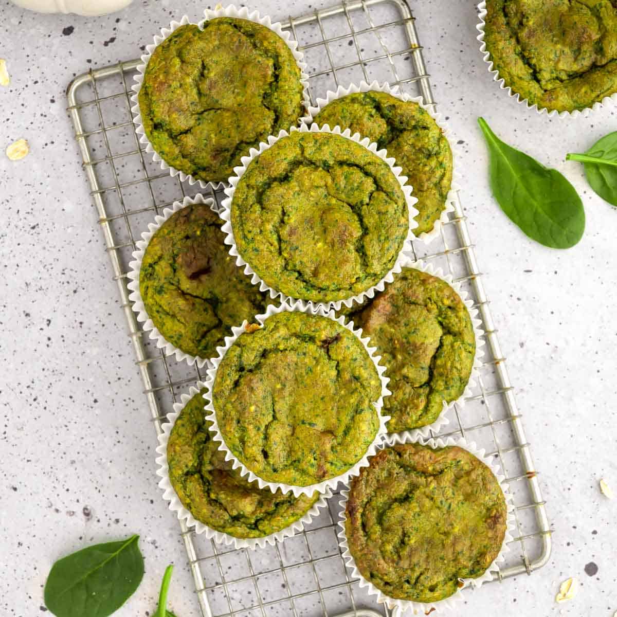 A batch of beautiful green spinach banana muffins on a cooling rack.