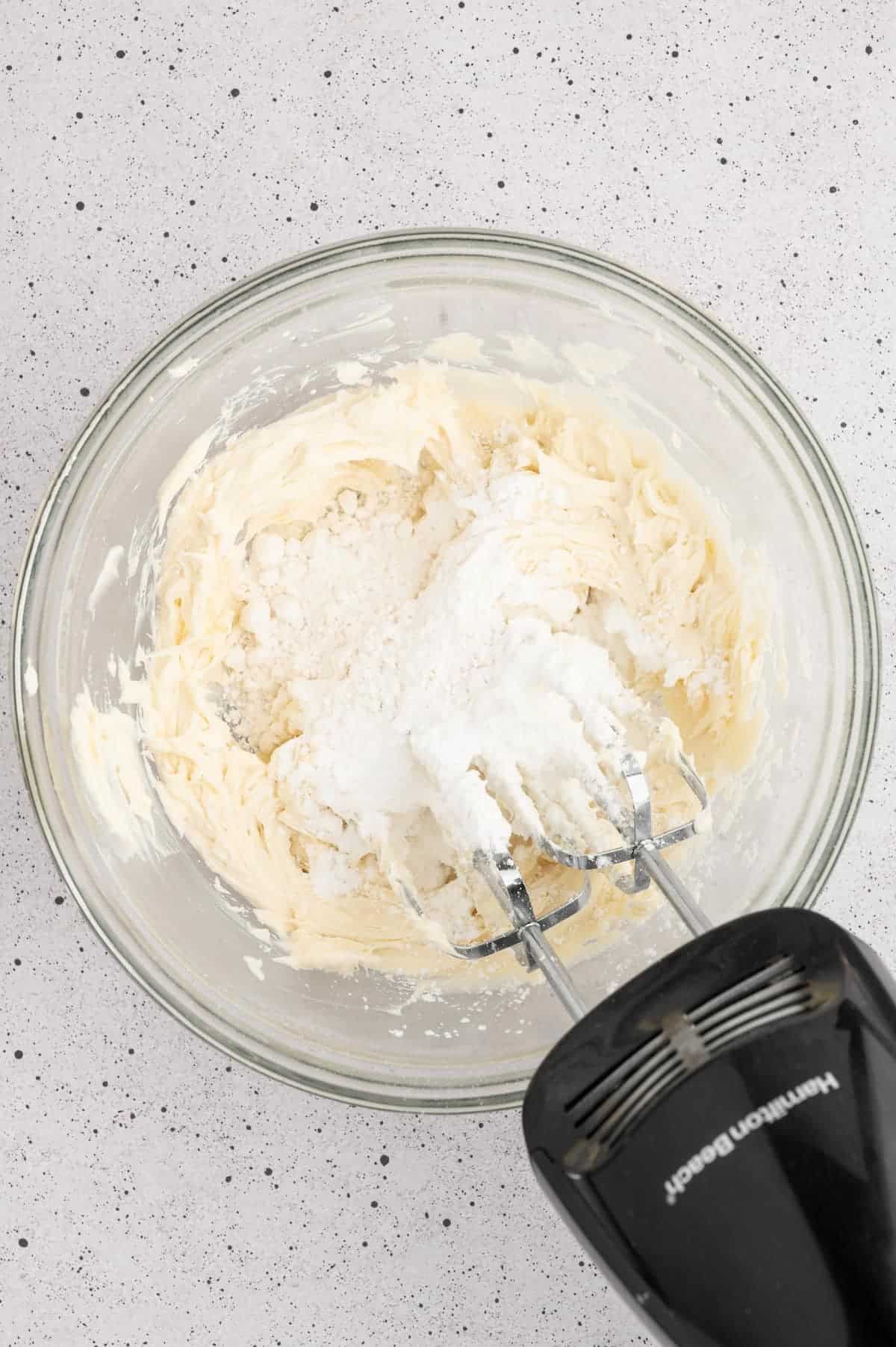 Half cup of powdered sugar added to the top of the creamed vegan butter in a bowl.