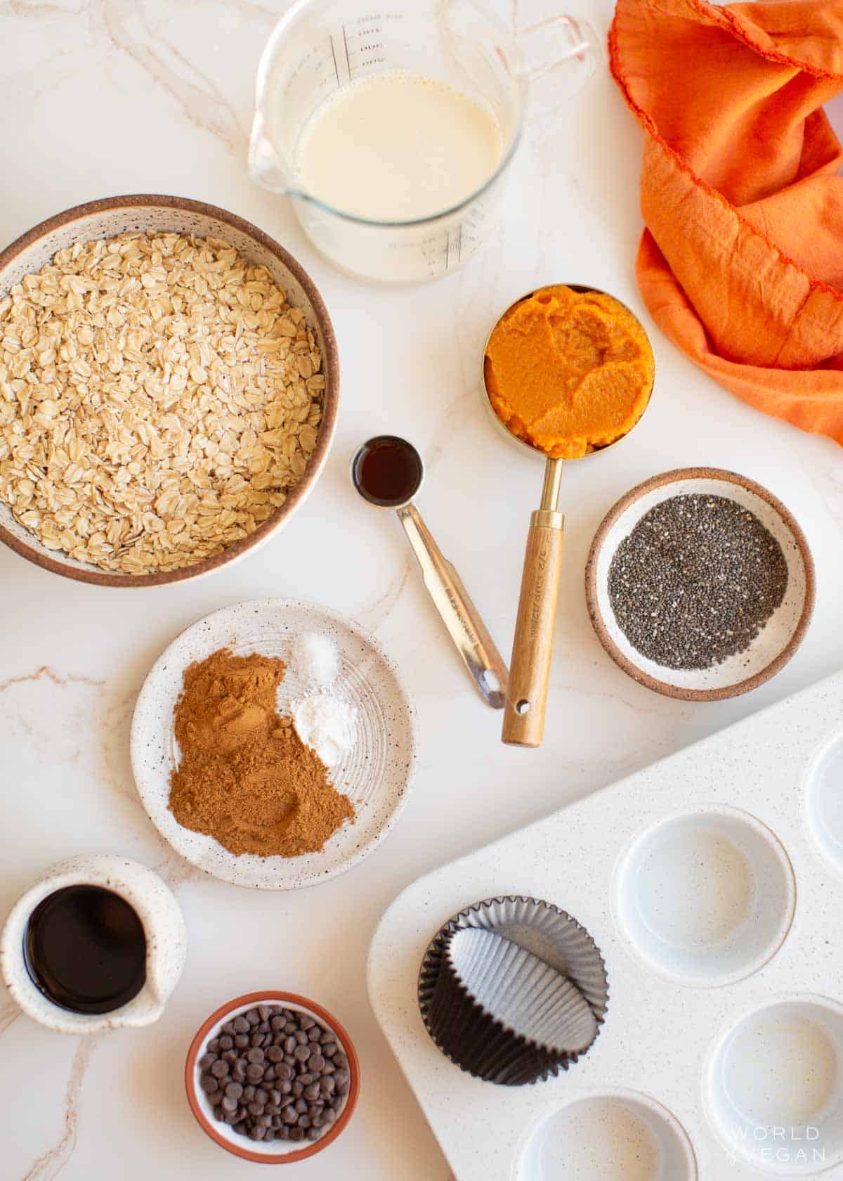 Ingredients for pumpkin baked oatmeal bites measured out in various bowls and cups.
