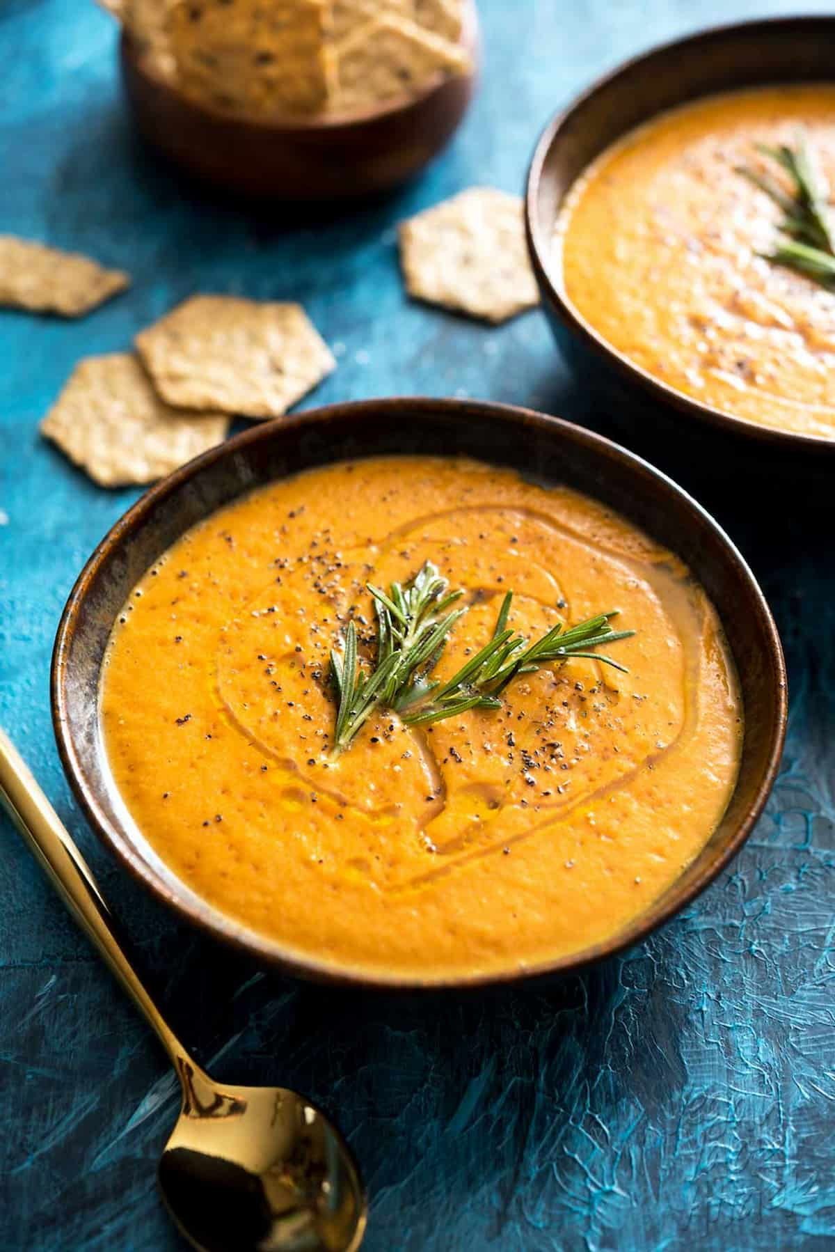 A bowl of tomato bisque garnished with fresh herbs.