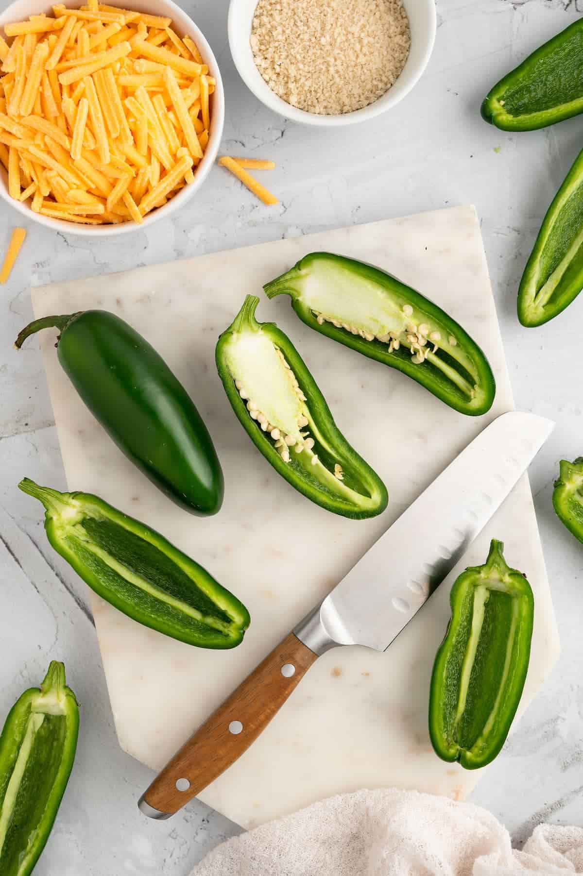 A town-down shot of halved jalapeno peppers against a marble background.