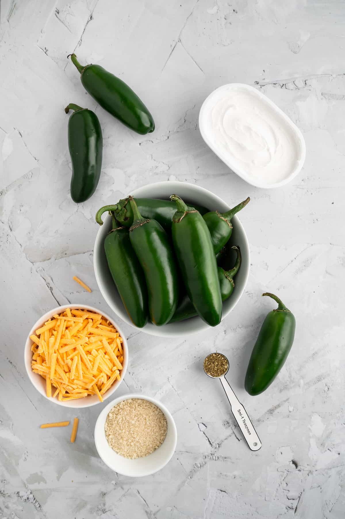 A top-down shot of ingredients for jalapeno poppers against a marble background.