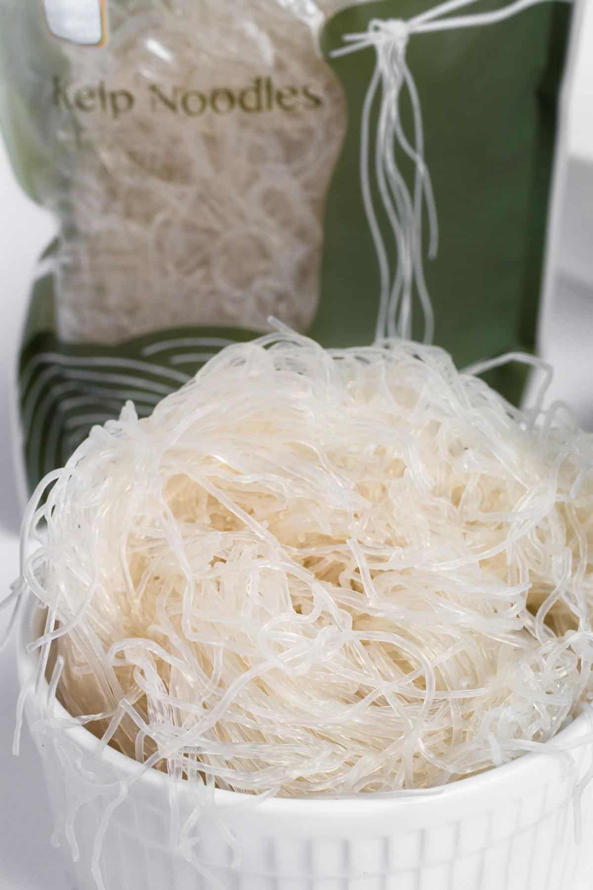 Prepared kelp noodles in a bowl with the packaging behind it.