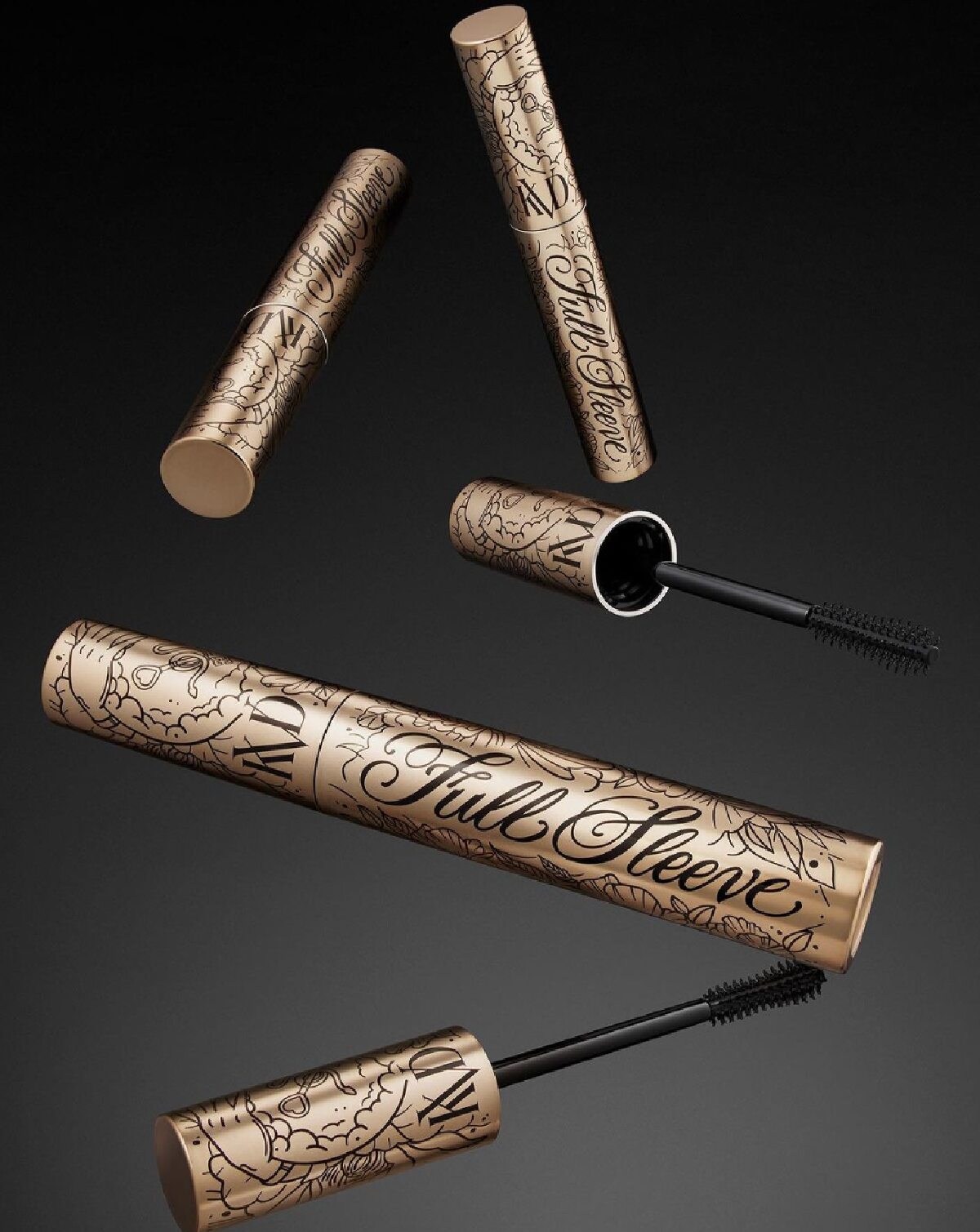 Gold tubes of KVD Beauty Full Sleeve vegan mascara in mid air against a black and gray background. 
