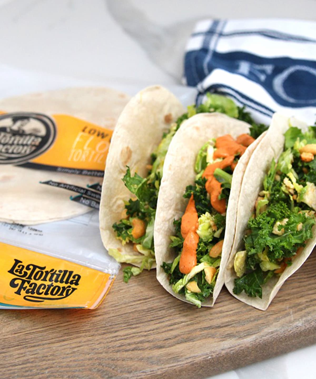 A package of La Tortilla Factory tortillas next to three kale tacos.