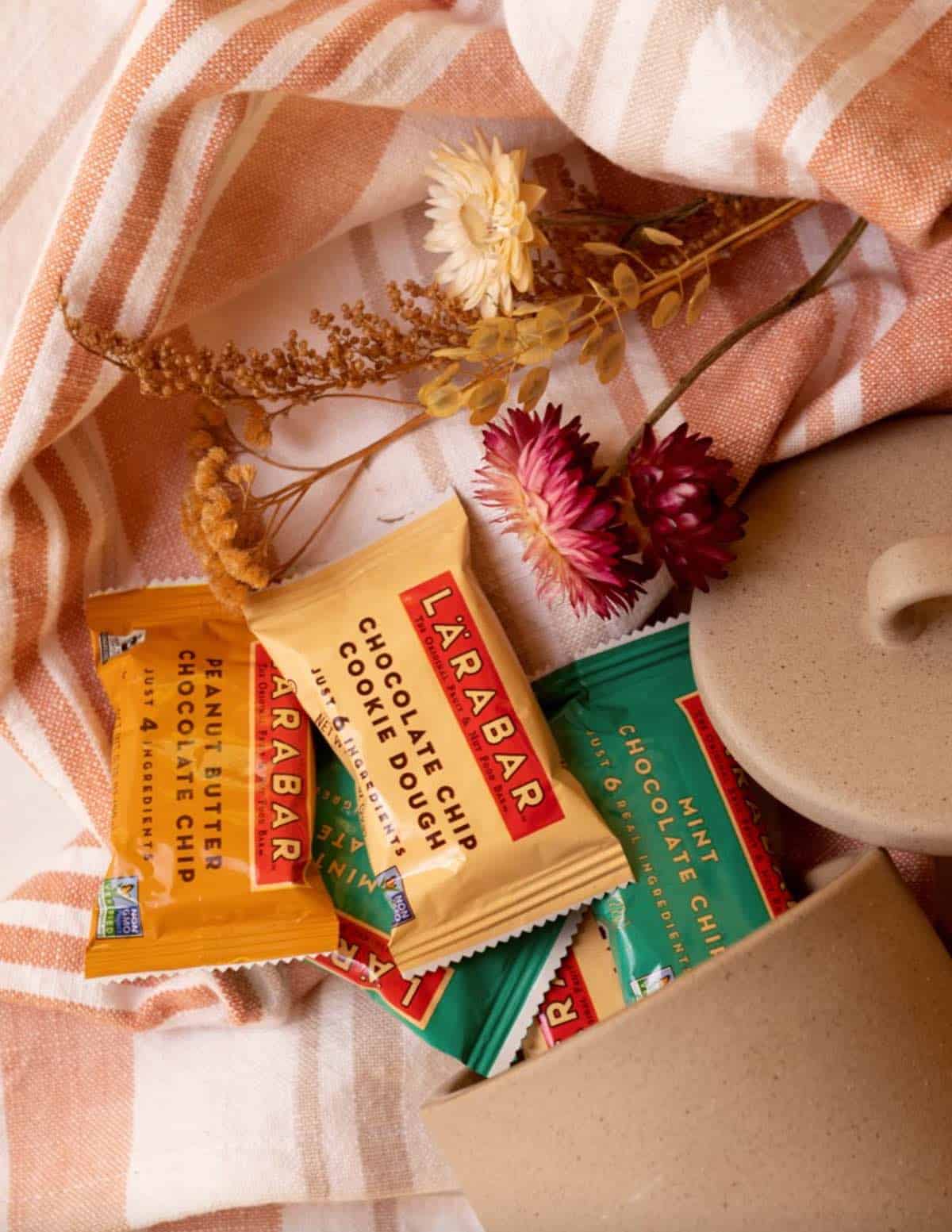 An assortment of healthy larabar protein bars coming out of a kitchen jar. 