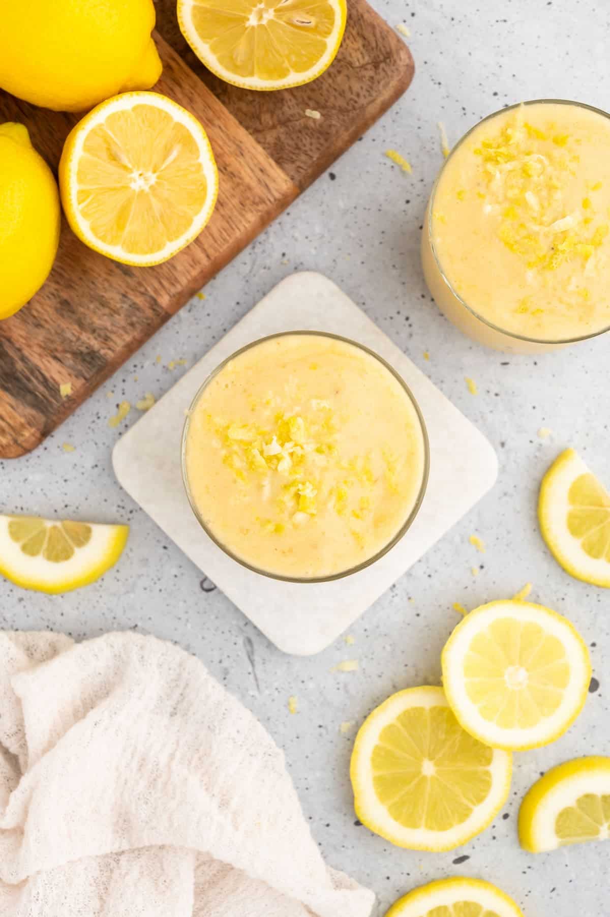 Lemon smoothie on a coaster, topped with lemon zest.