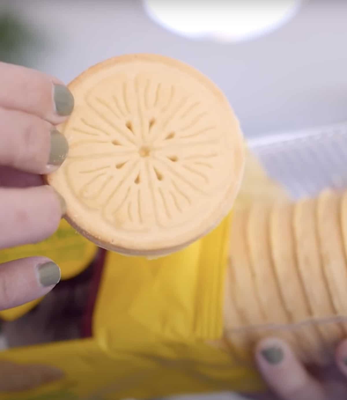 Holding out an open package of vegan Lemonades cookies from Girl Scouts. 