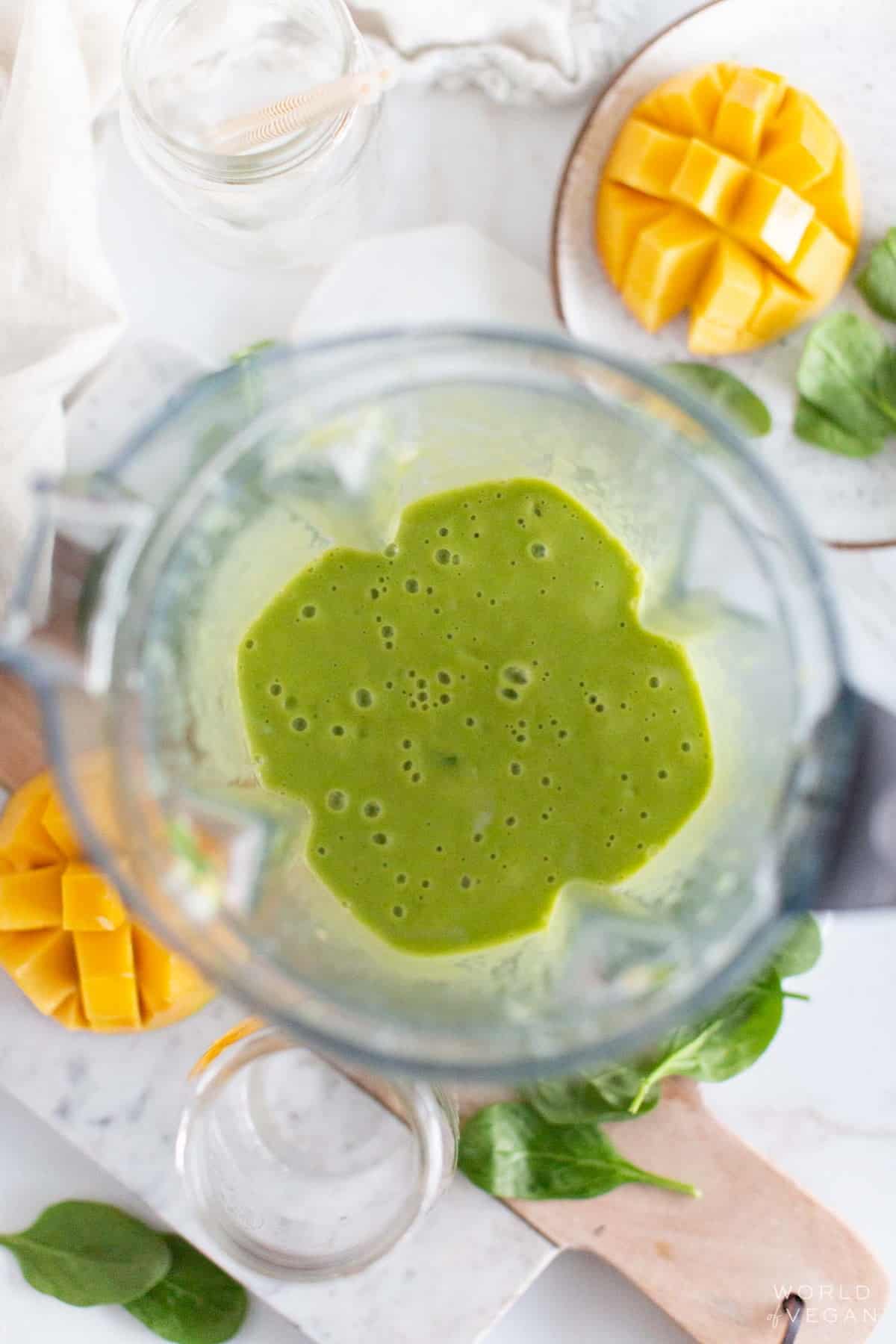 Vitamix blender with green smoothie and mango. 