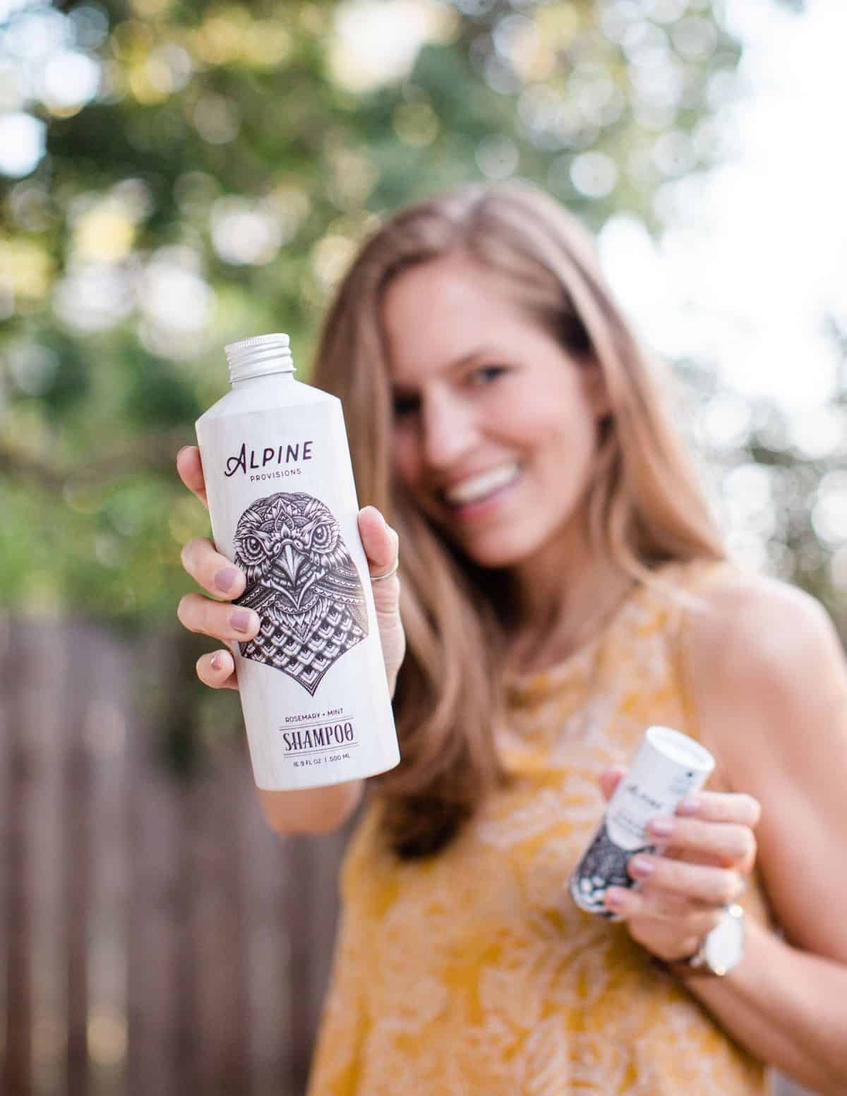 Michelle Cehn holding up cruelty-free and vegan sustainable body wash and shampoo from Alpine Provisions. 