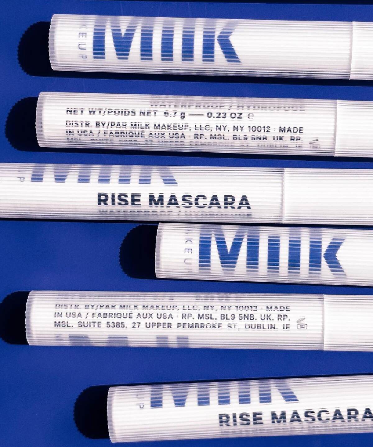 White Milk Makeup mascara tubes with blue writing against a blue background. 